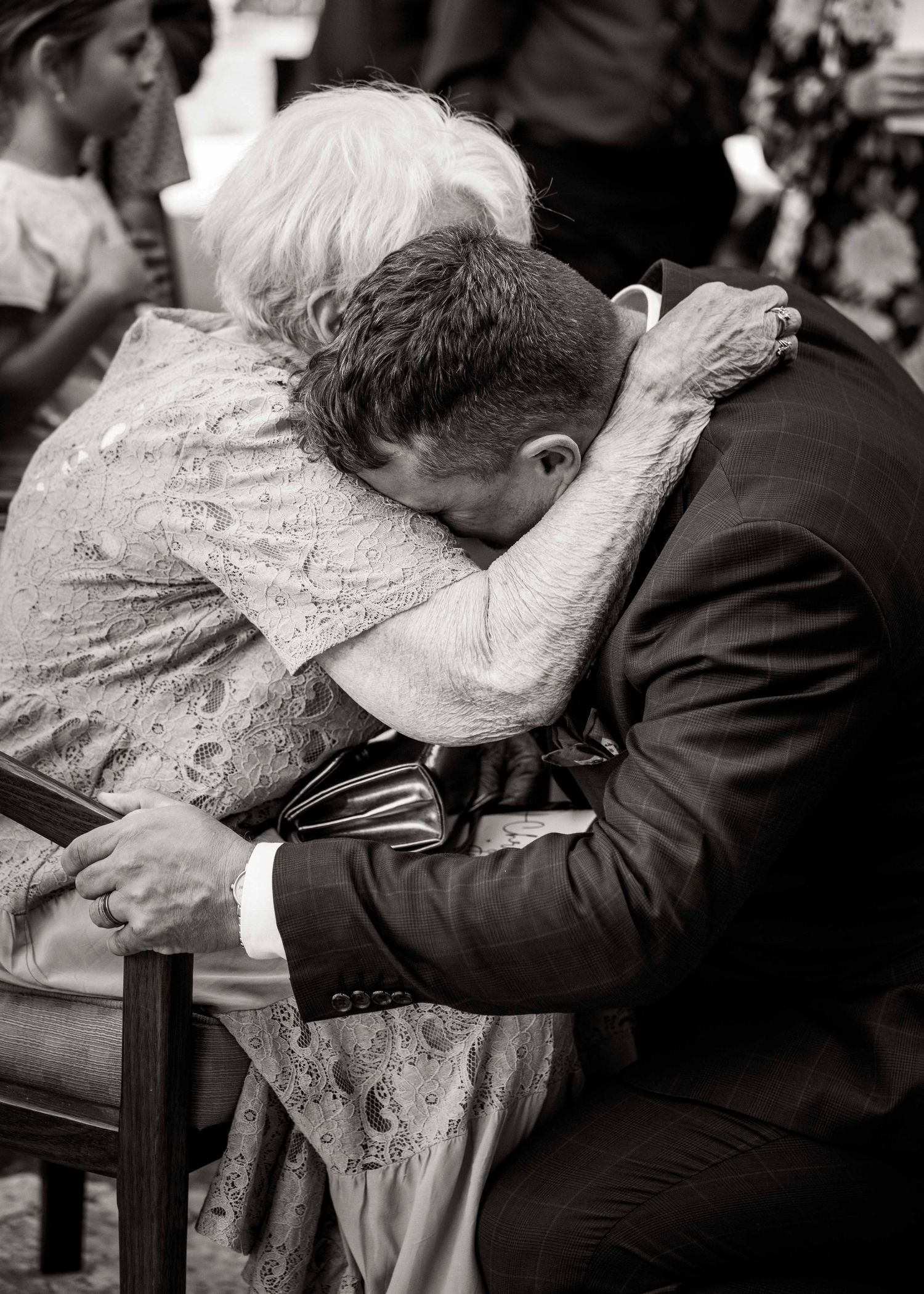 Black and white image series shows couple resting their heads intimately on wedding reception table.