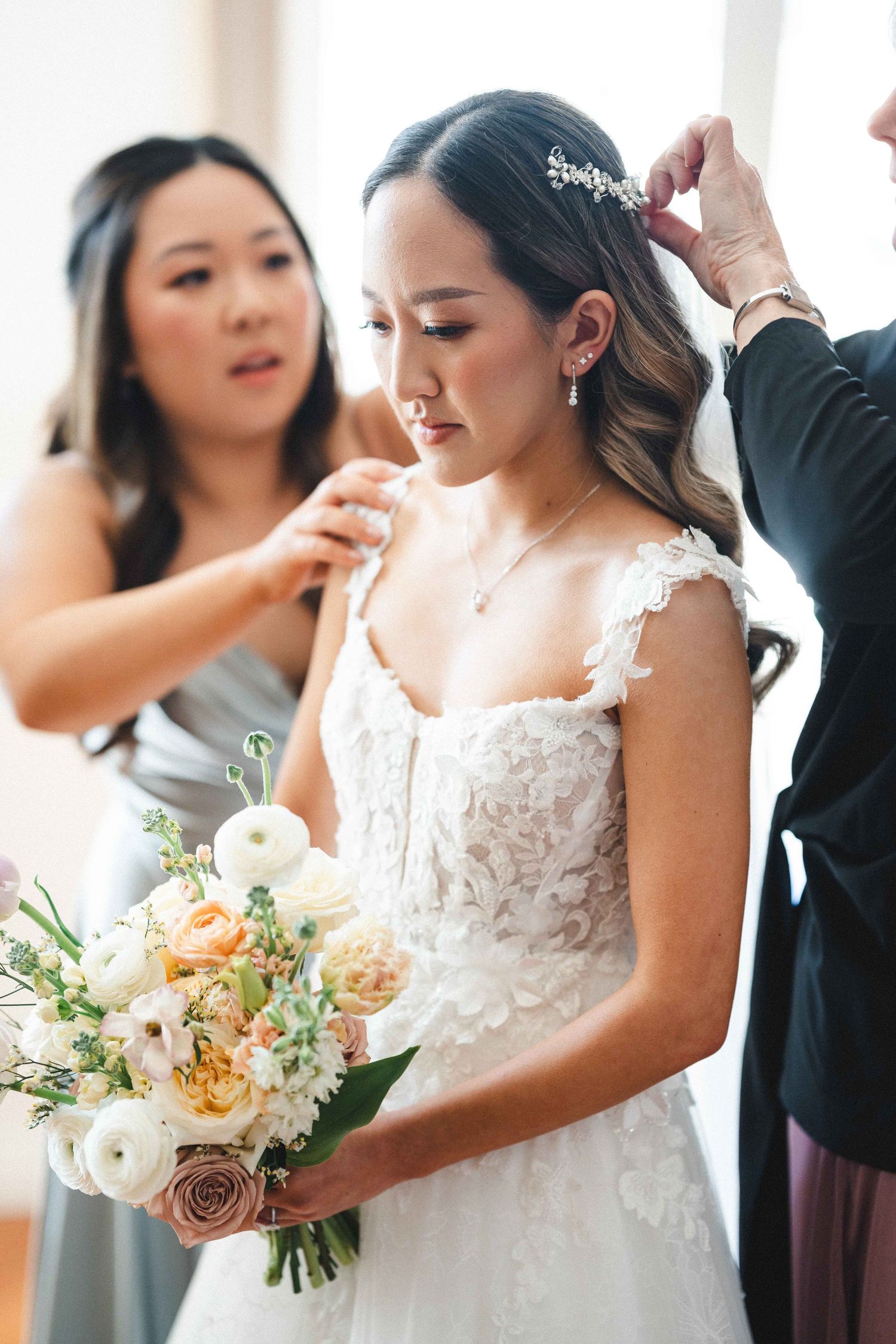 Wedding party bridal bouquet details with peach and cream colored florals in soft natural light during preparations.