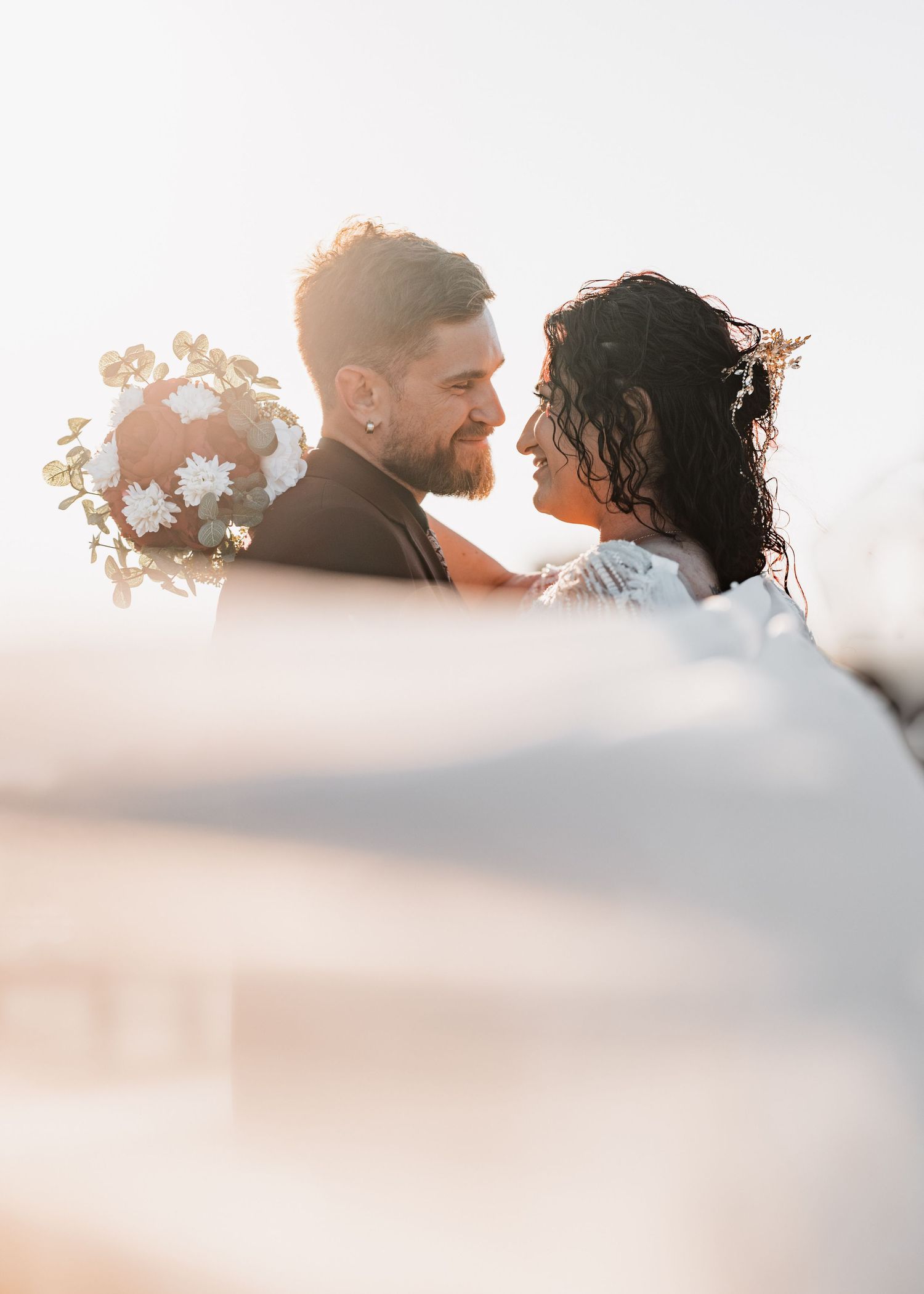A couple sharing a tender moment outdoors during golden hour with soft warm lighting.