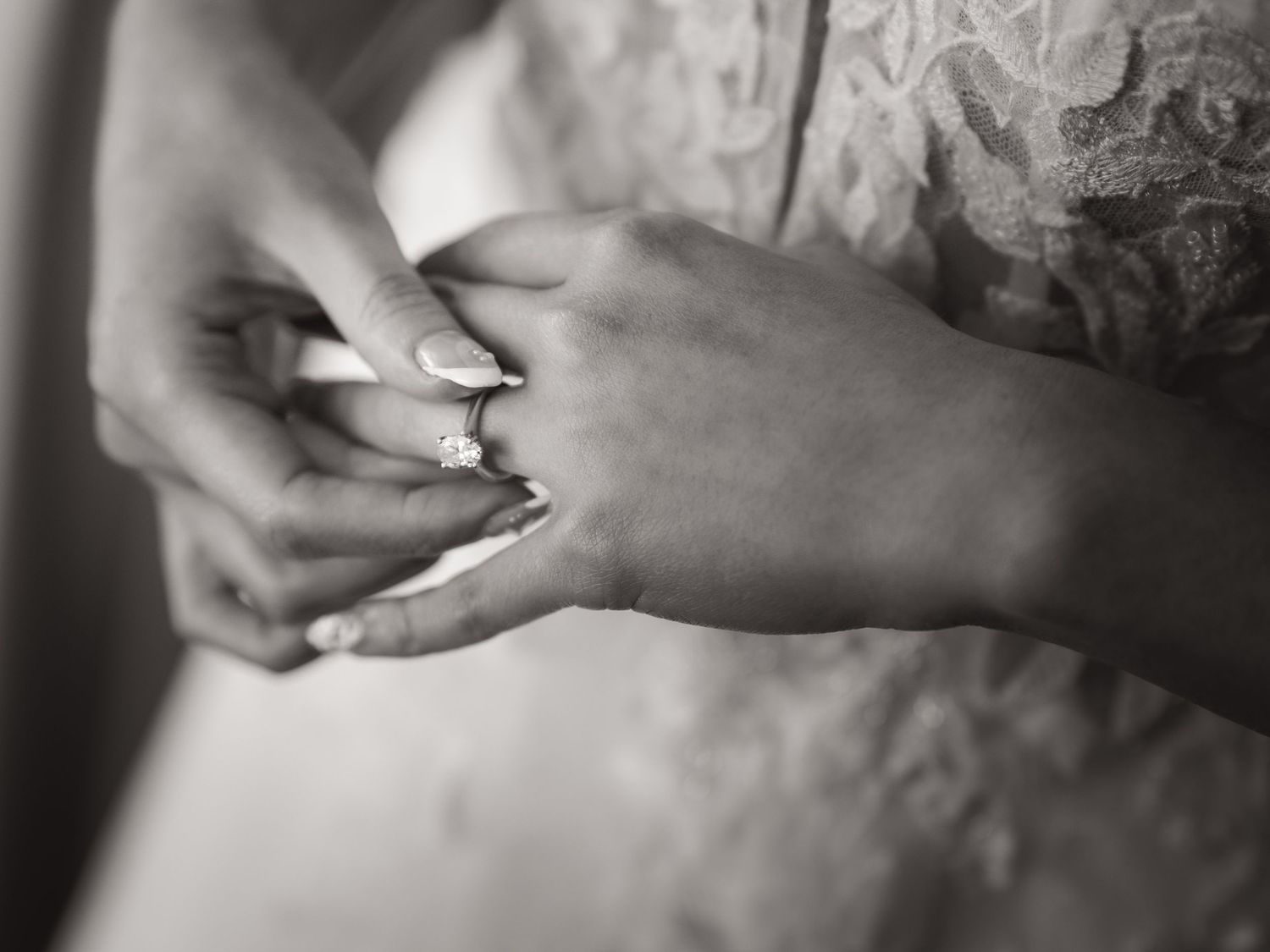 Close-up black and white photo of hands exchanging wedding rings during ceremony.
