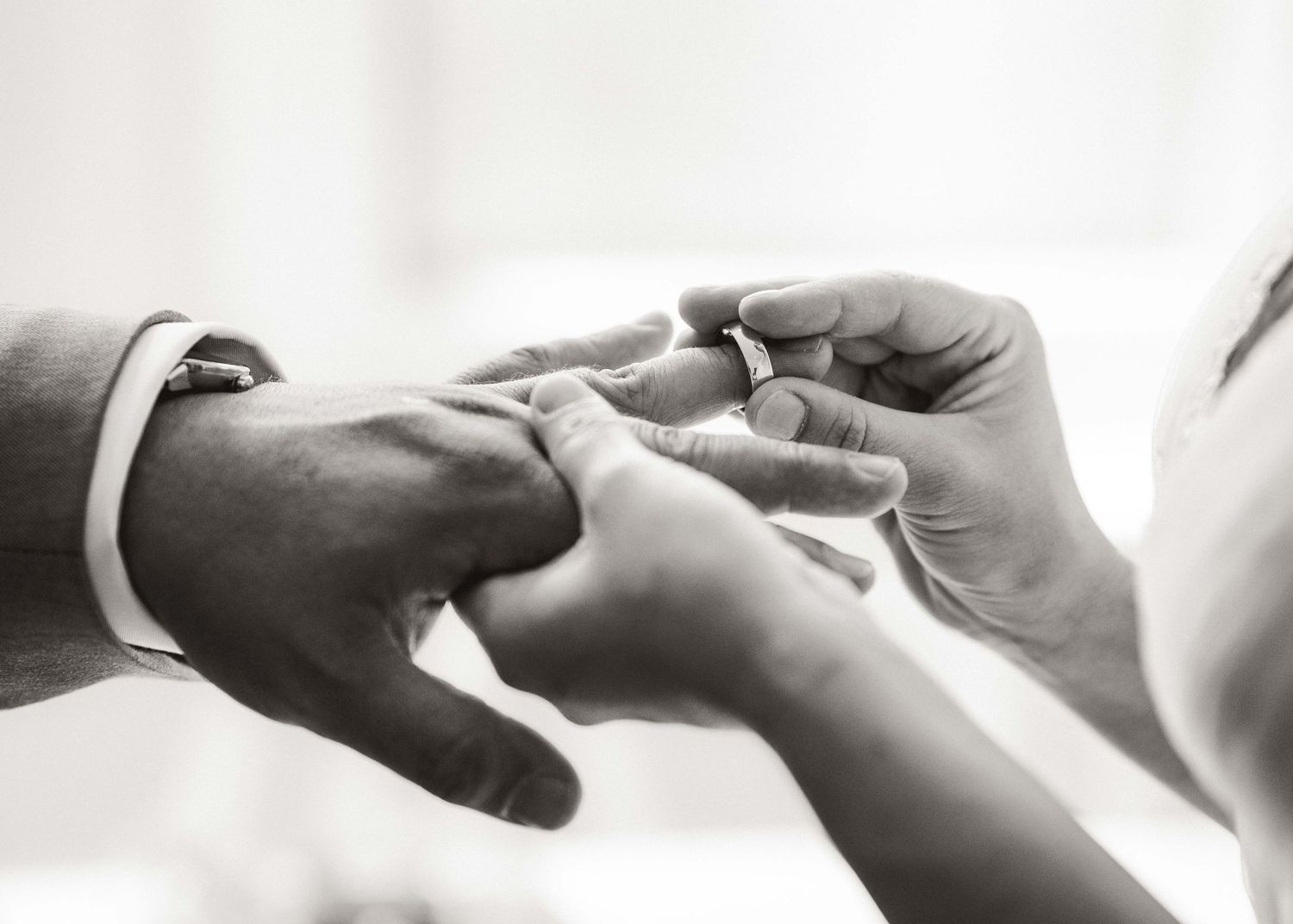Close-up shots of wedding ring exchange ceremony in black and white.