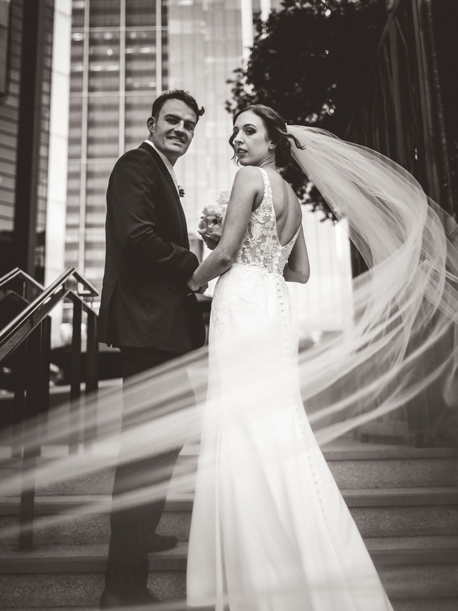 Black and white wedding portraits with flowing veil creating dramatic movement.