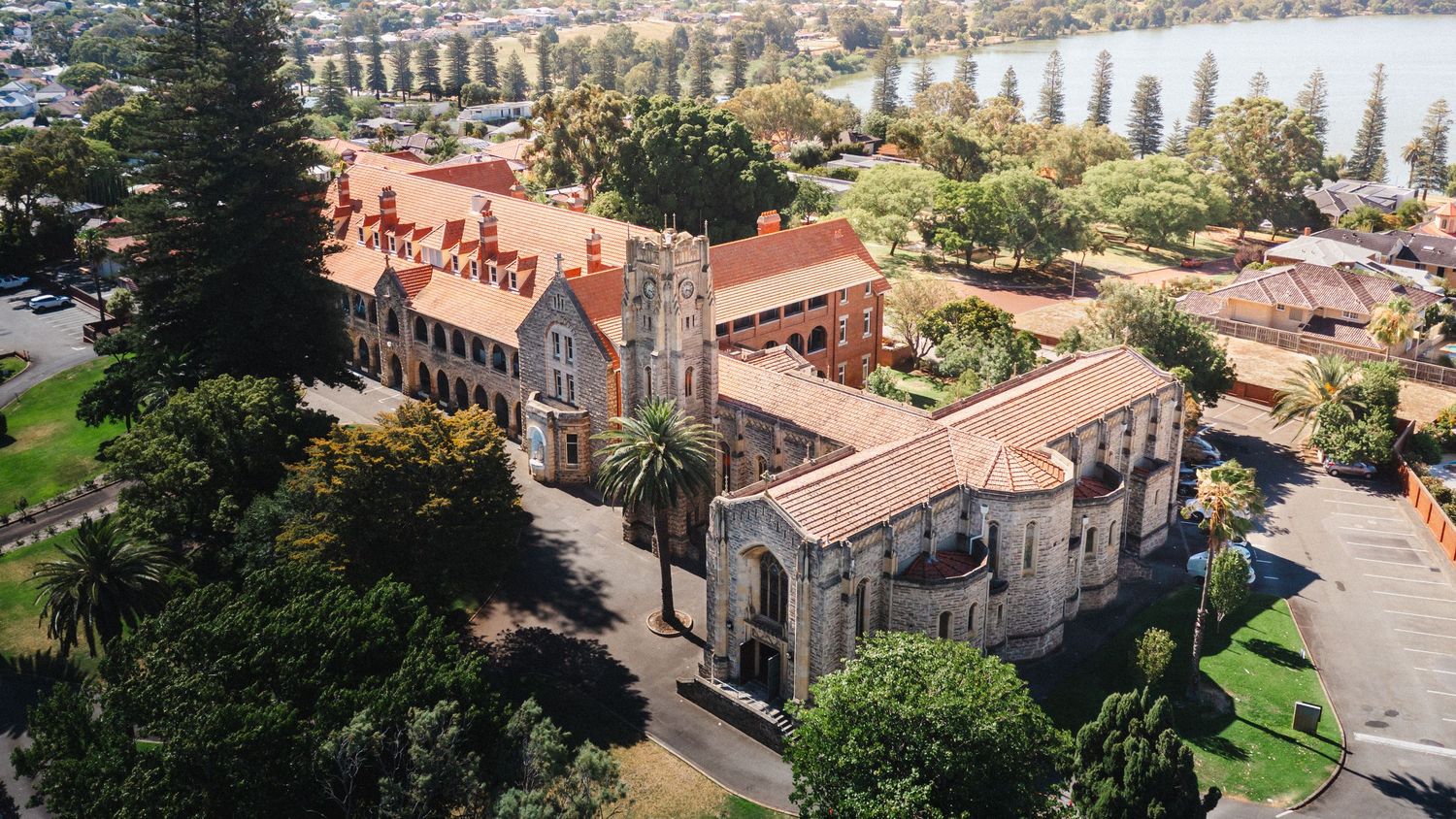 Panoramic aerial view of a historic lakeside town with red-roofed buildings and evergreen trees along the waterfront.