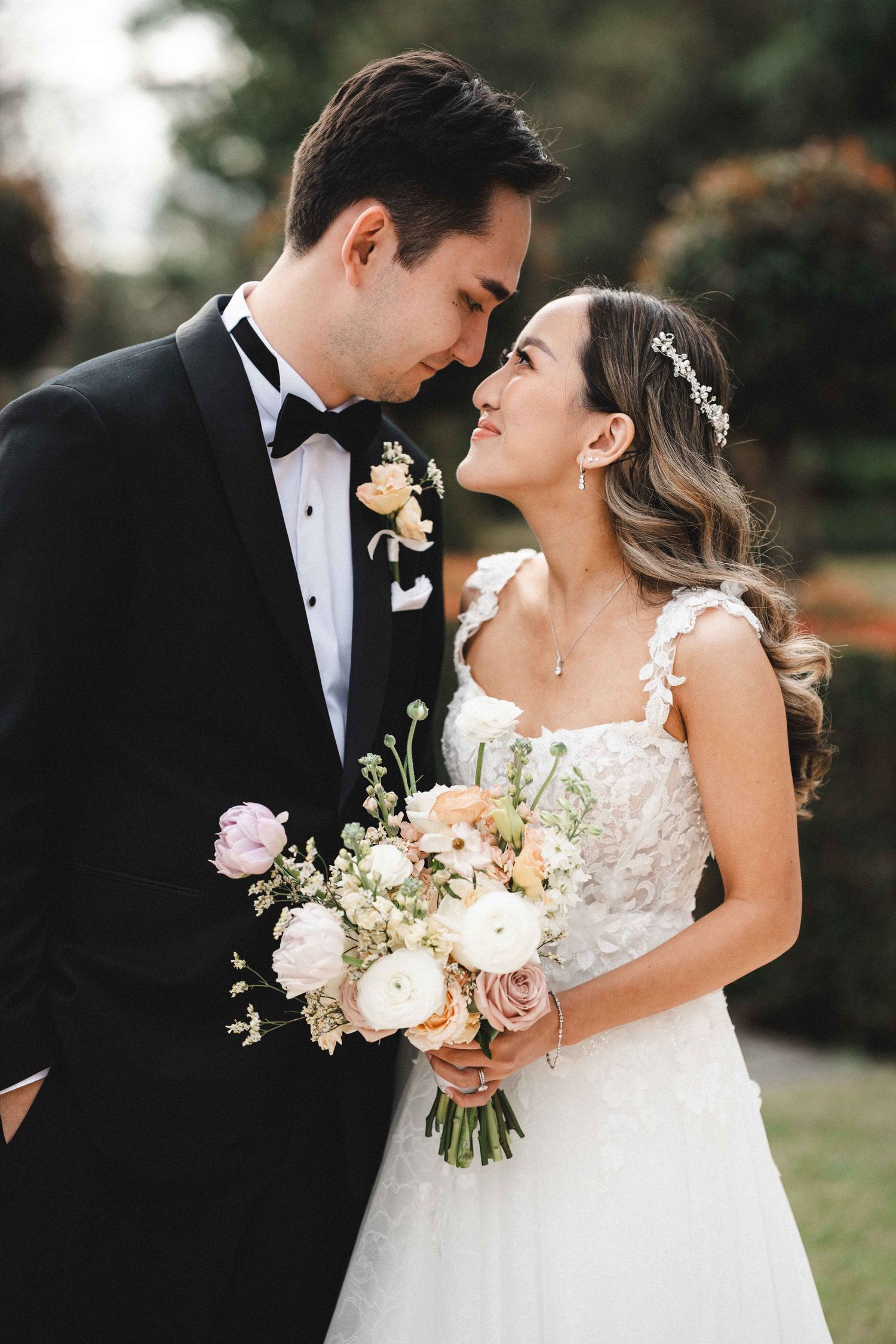 A romantic wedding couple shares intimate moments in formal attire with pink and white floral bouquet.