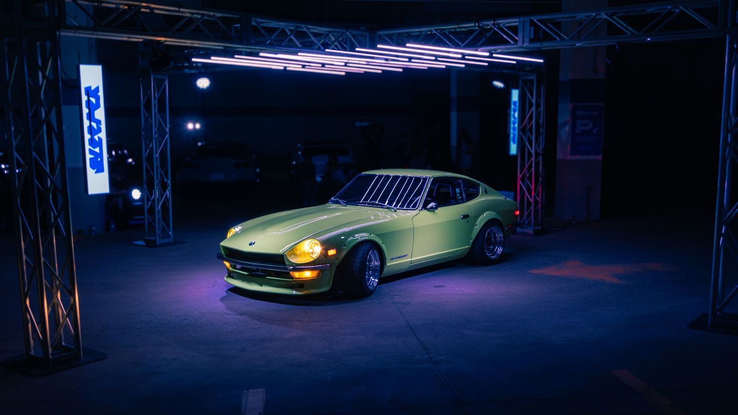 Classic lime green Nissan S30 240Z displayed under dramatic purple lighting at a car show.