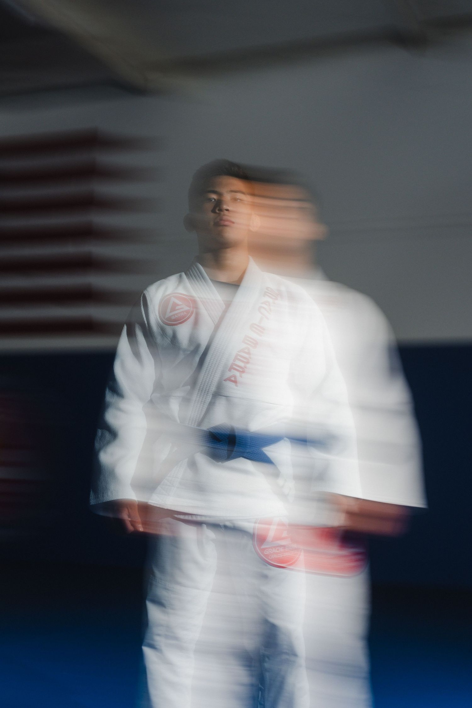 Motion blur portrait of martial artist in white gi uniform against dark background.