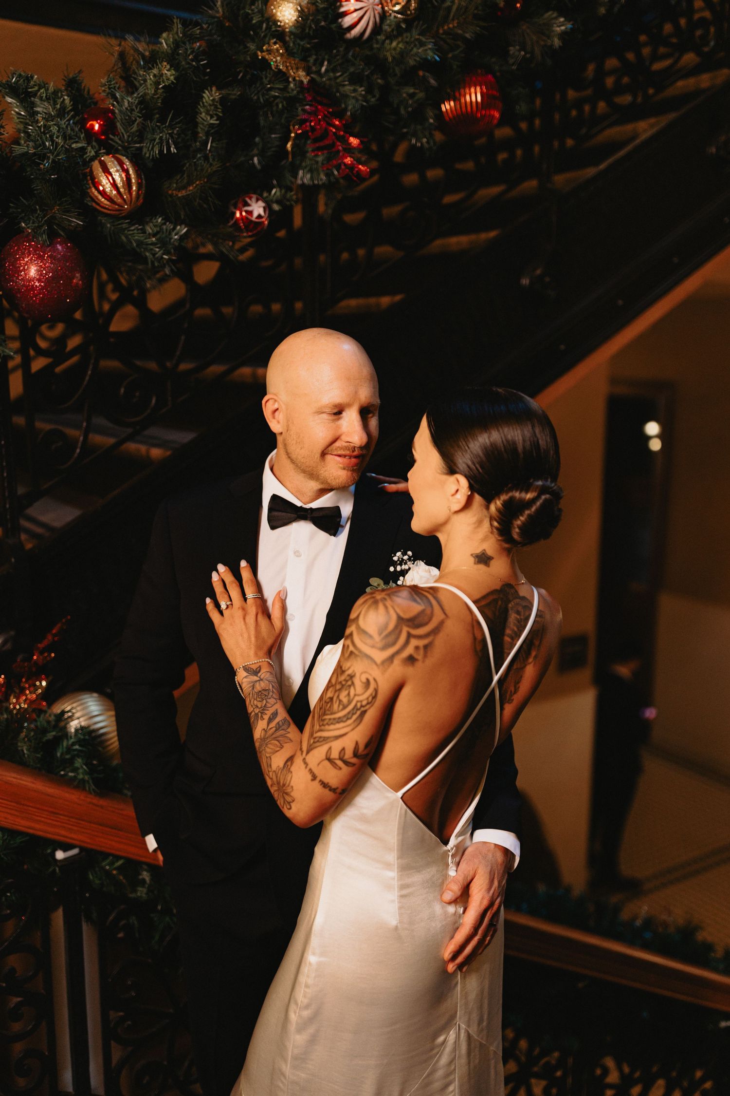 A romantic wedding couple shares an intimate dance moment under decorative lighting at an evening reception.