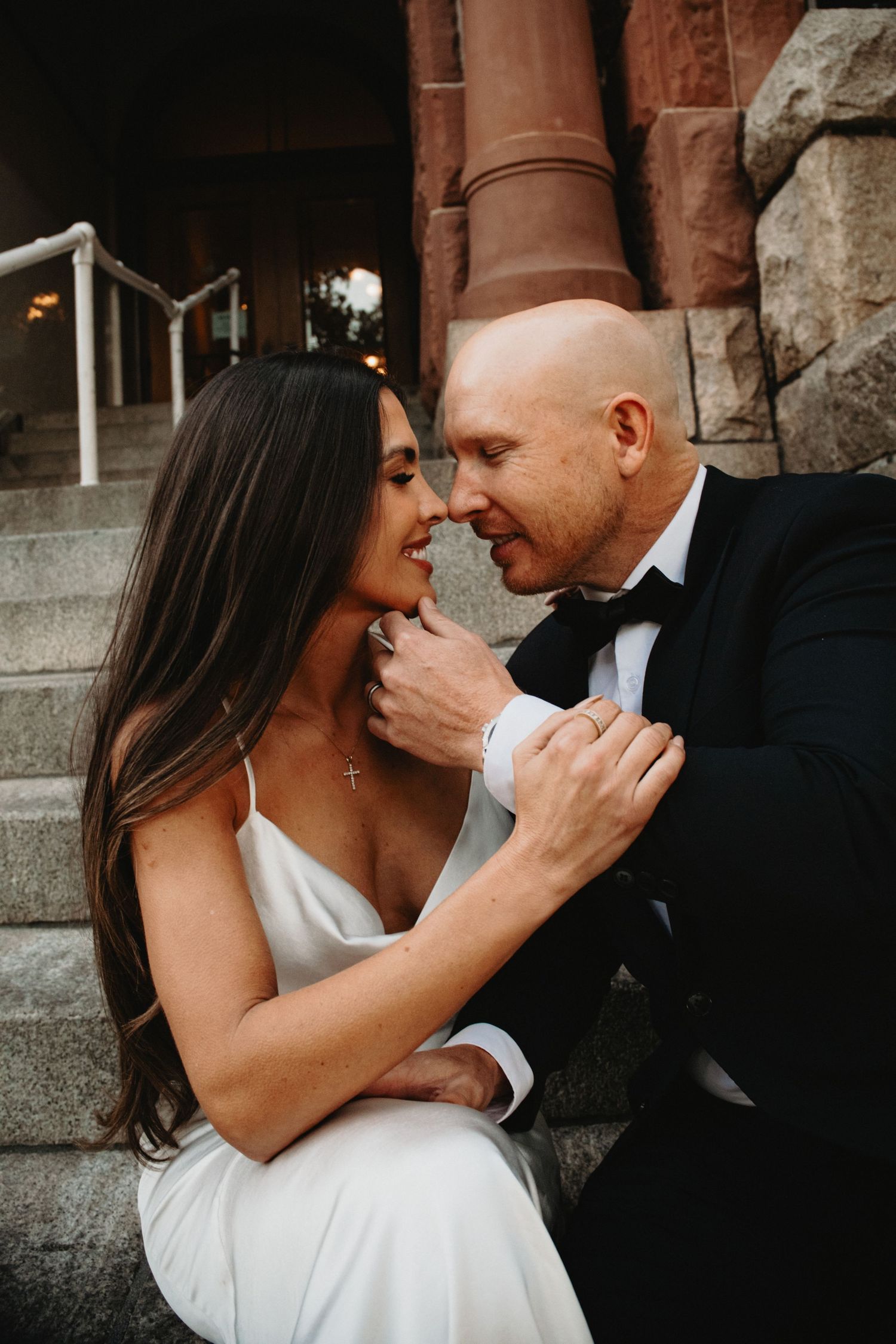 Romantic wedding couple shares intimate moments against stone wall in series of candid portrait photographs.