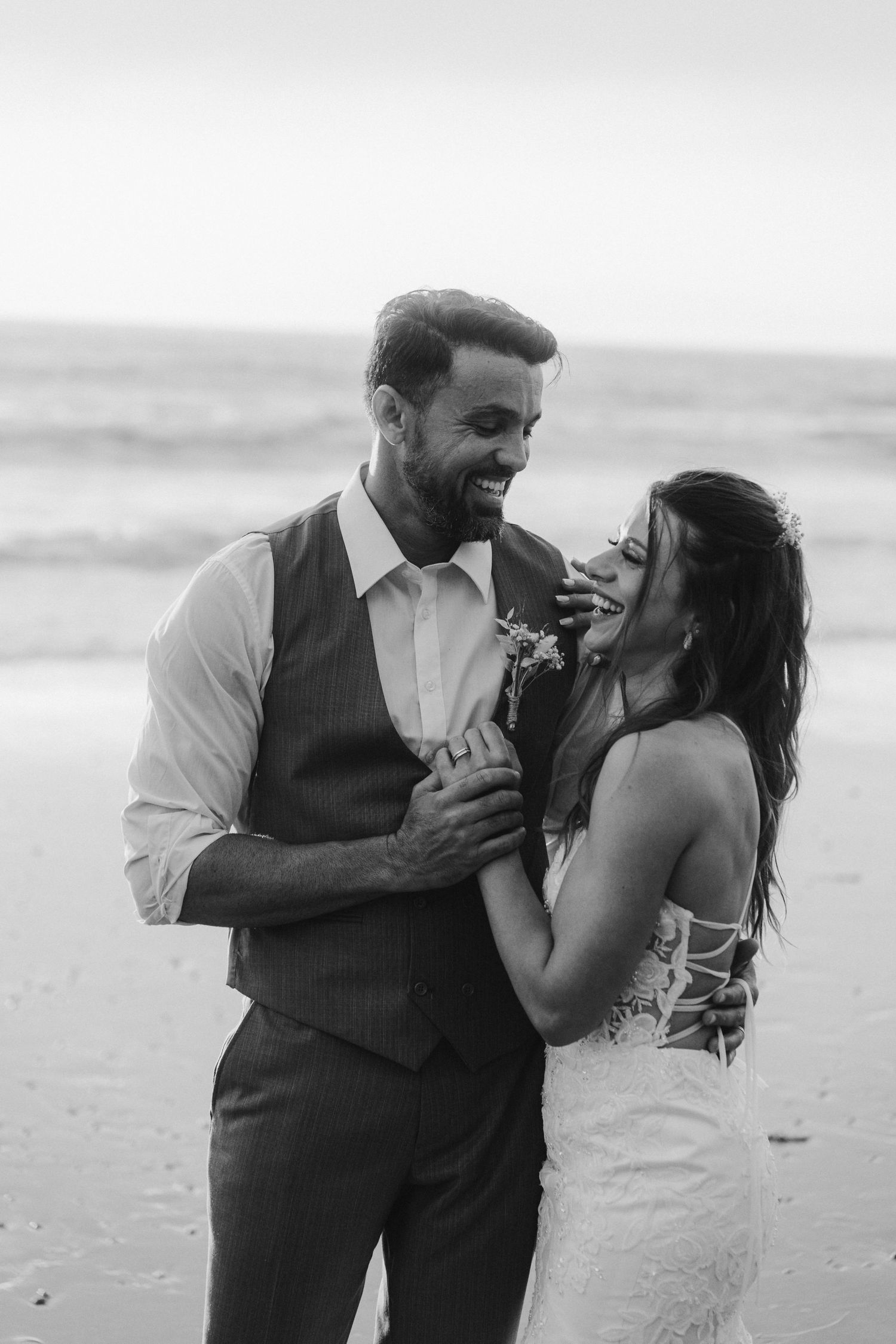 A couple shares intimate moments and laughter during their beach wedding photoshoot.