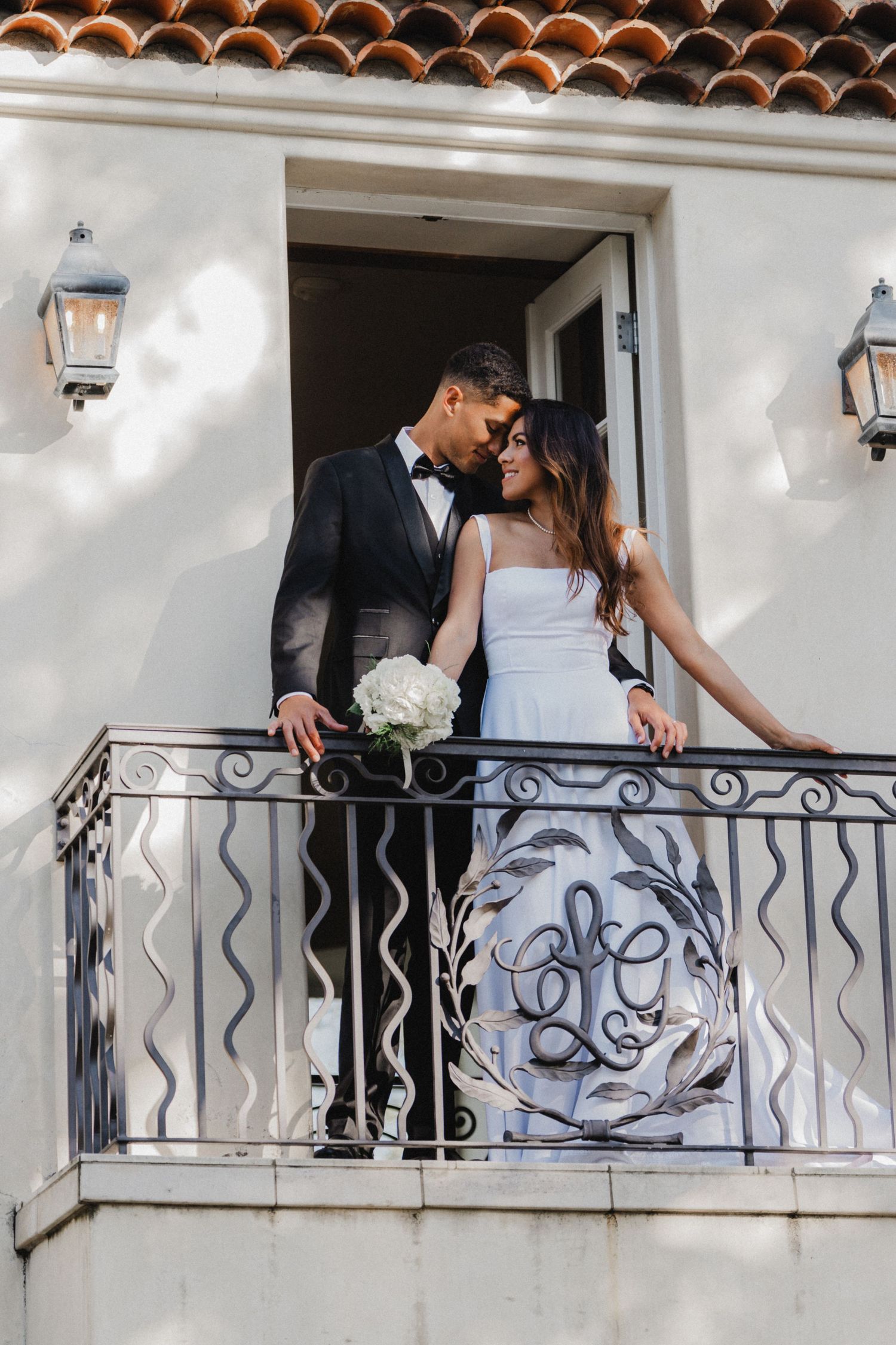 Romantic moment shared on Mediterranean style balcony with wrought iron railing.