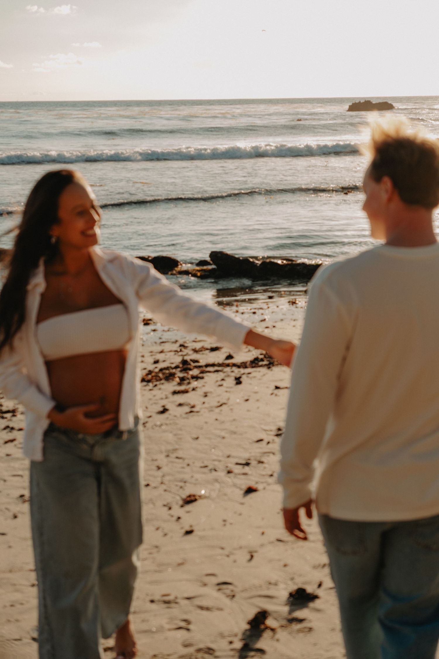 A sequence of photos showing two people embracing on a beach at sunset with ocean waves in the background.