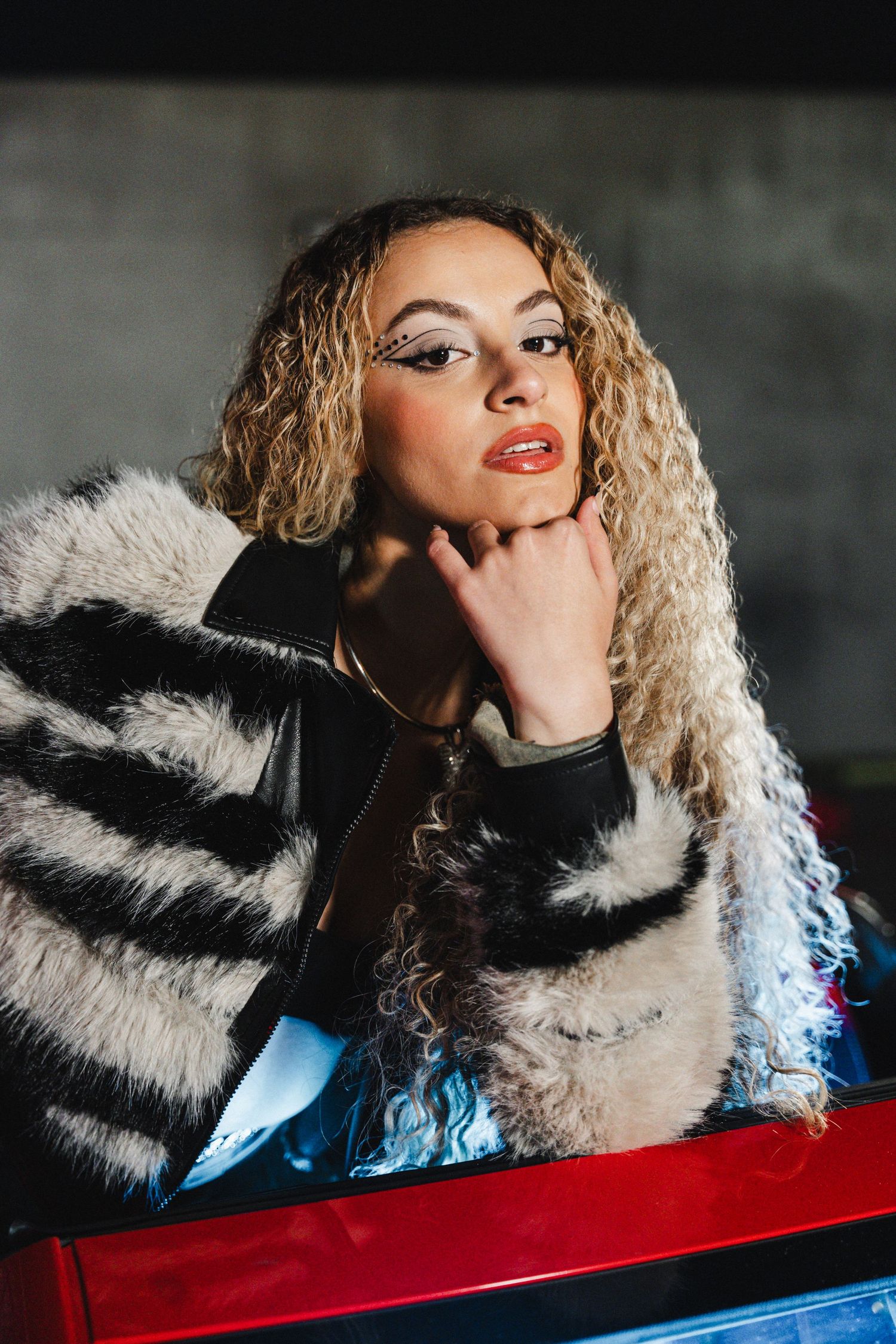Fashion portrait featuring striped fur coat and glamorous makeup against dark background.