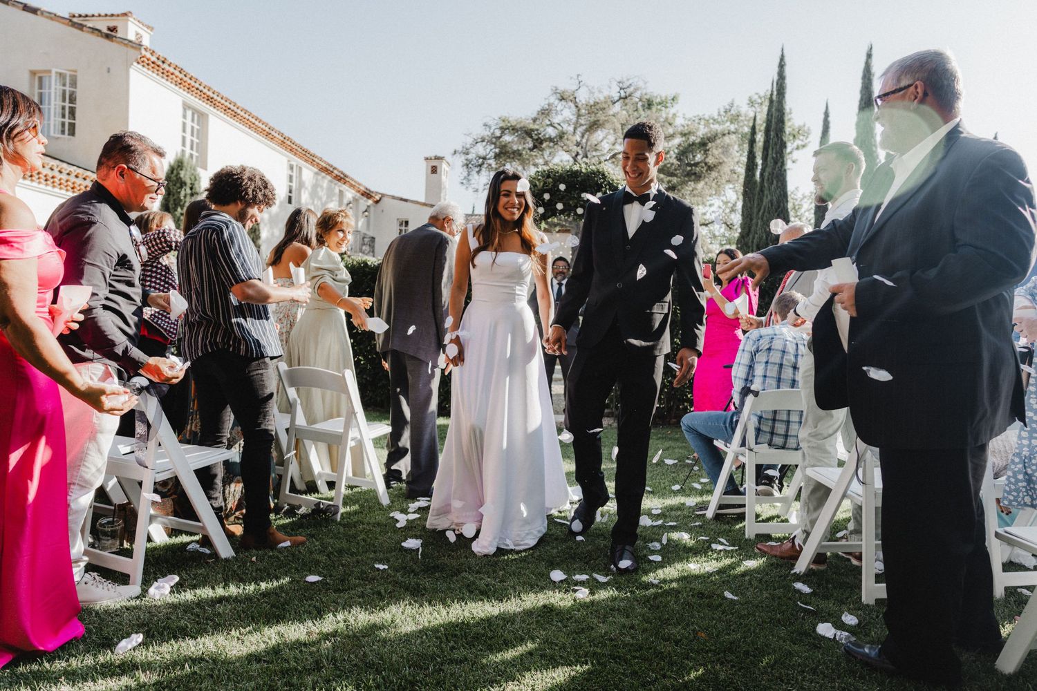 Wedding reception scene with guests mingling on a sunny lawn with decorative elements.