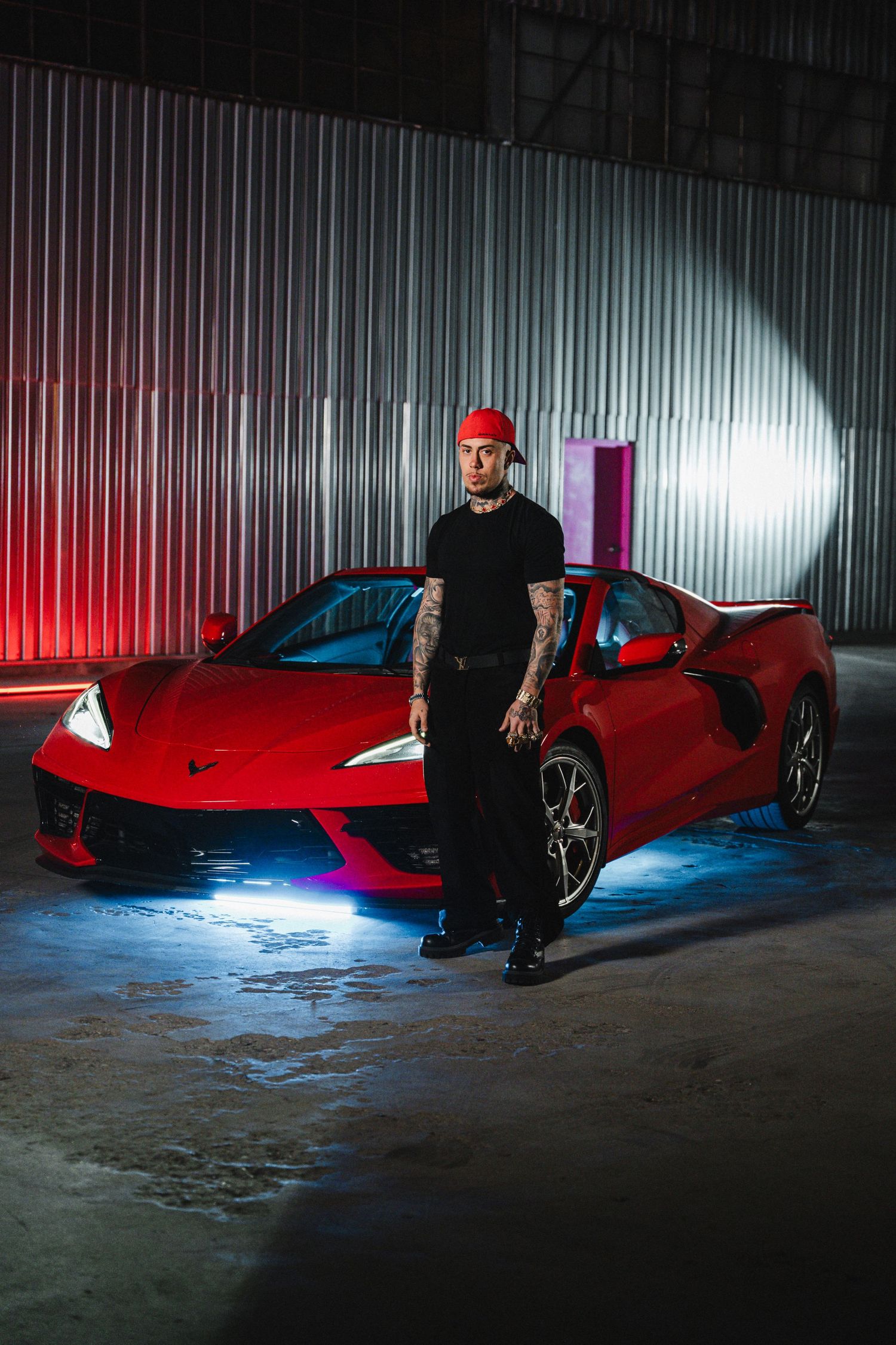 Red sports car in dramatic lighting with person standing beside it.