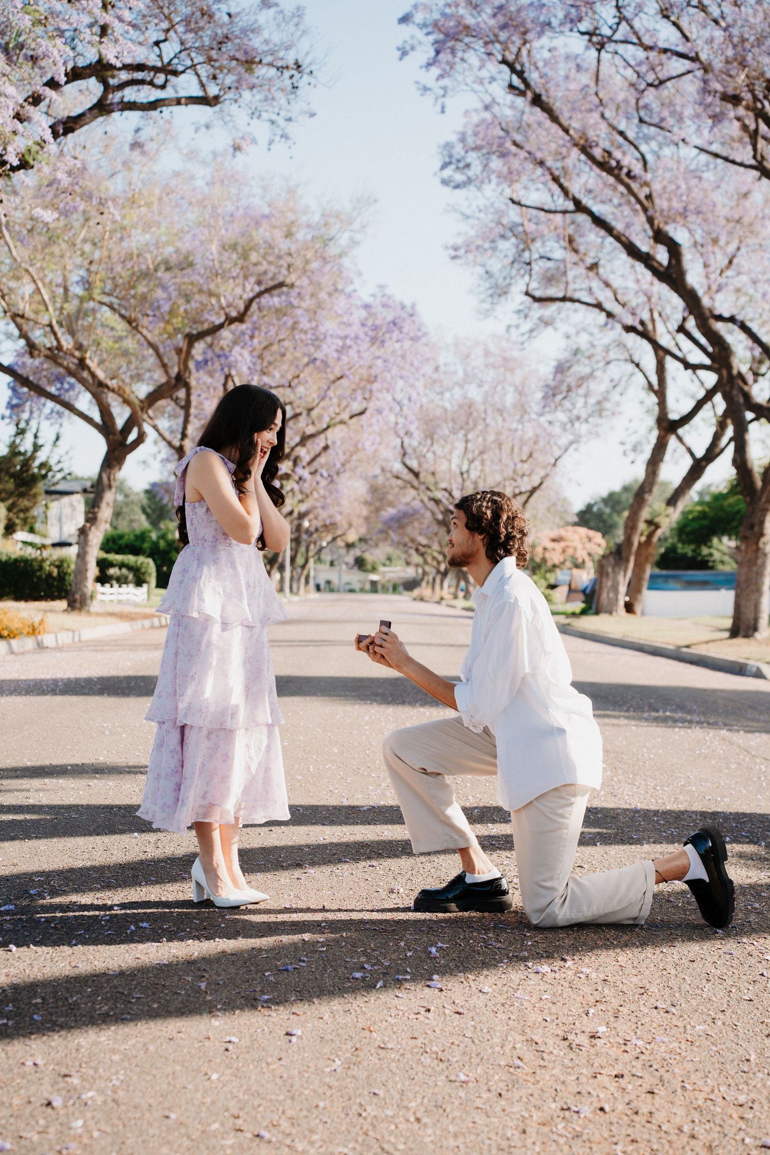 A surprise marriage proposal captured in sequence under pink blooming trees.