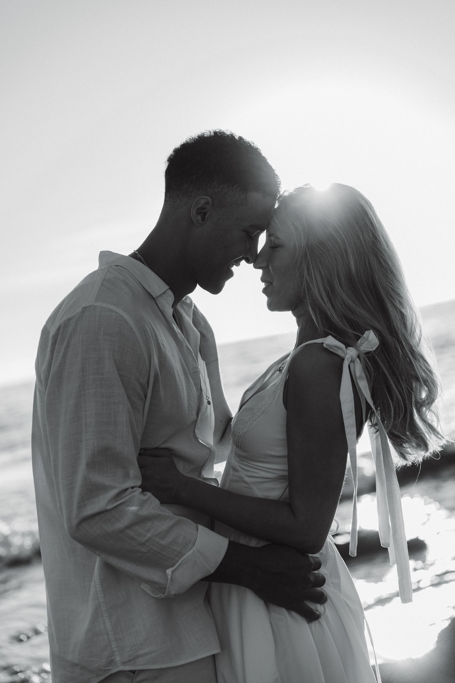 Black and white silhouette of a couple sharing an intimate moment against a bright background.