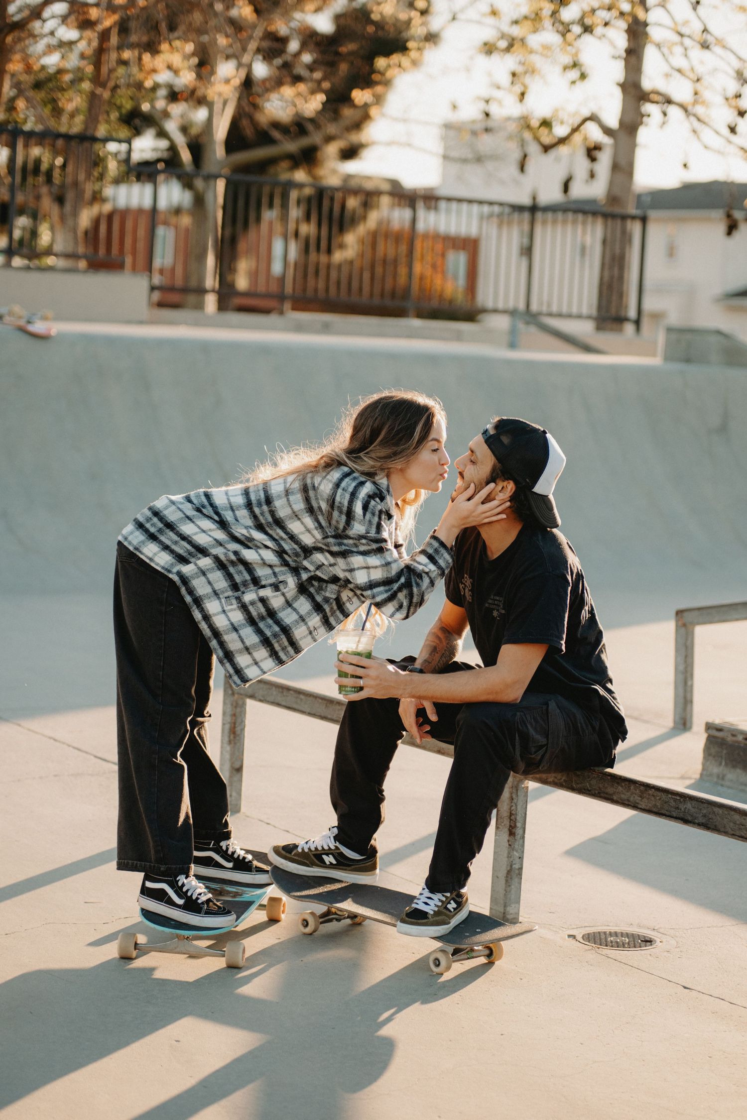 Two skateboarders share an intimate moment at a skate park during golden hour.