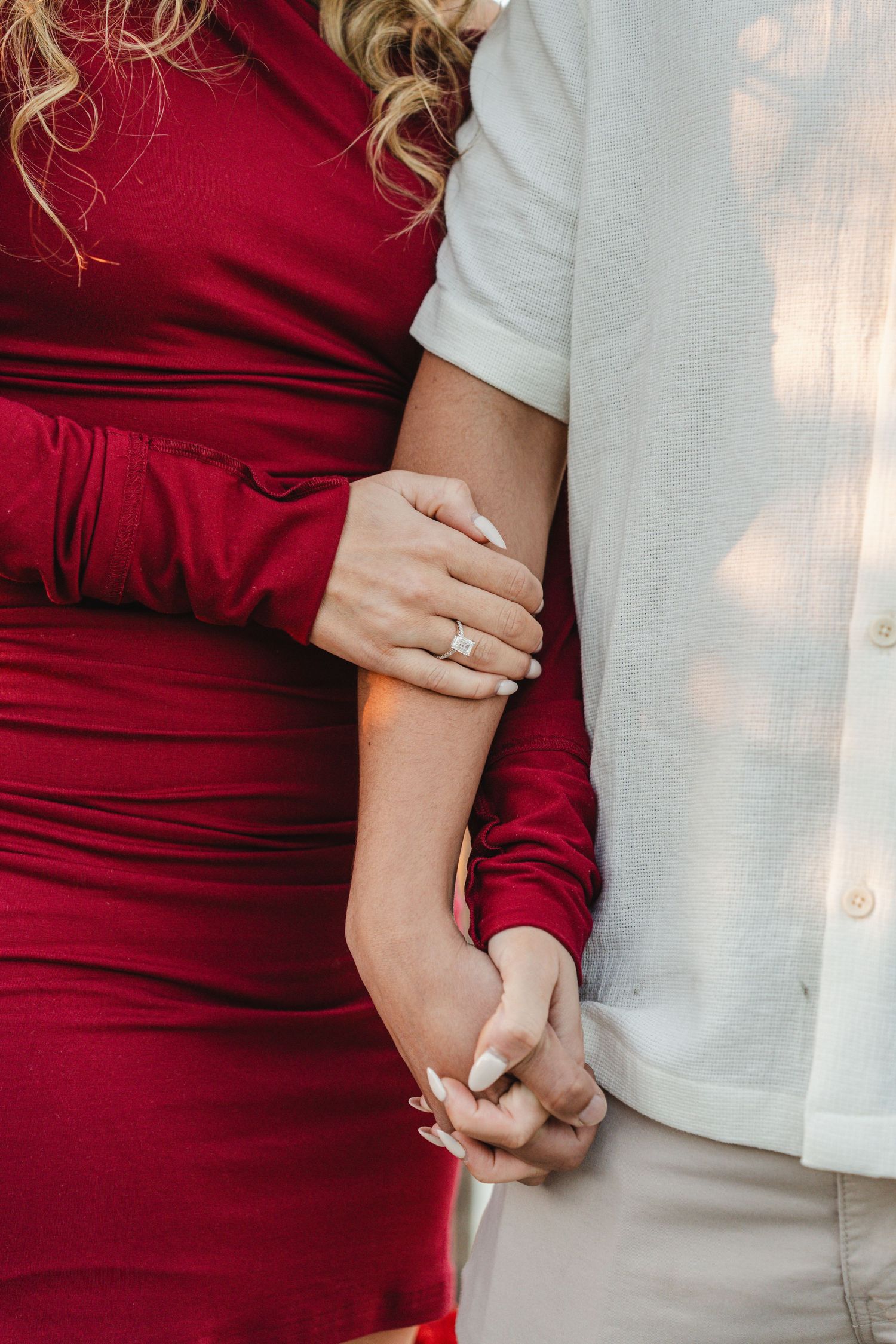 Close-up of couple embracing, showing red dress and white shirt details.