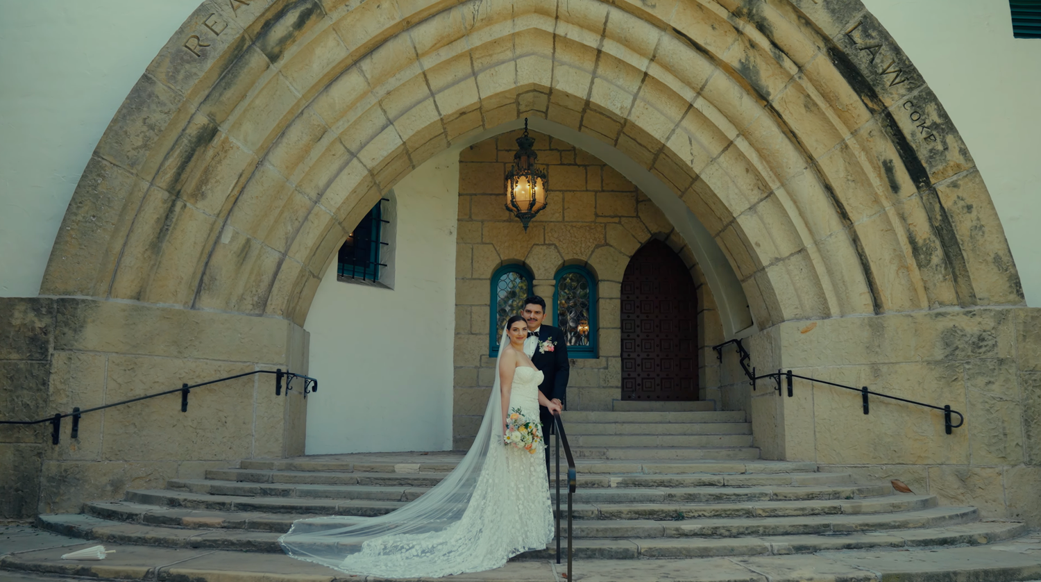 A panoramic view of a grand stone staircase with arched entryways in a historic building interior.