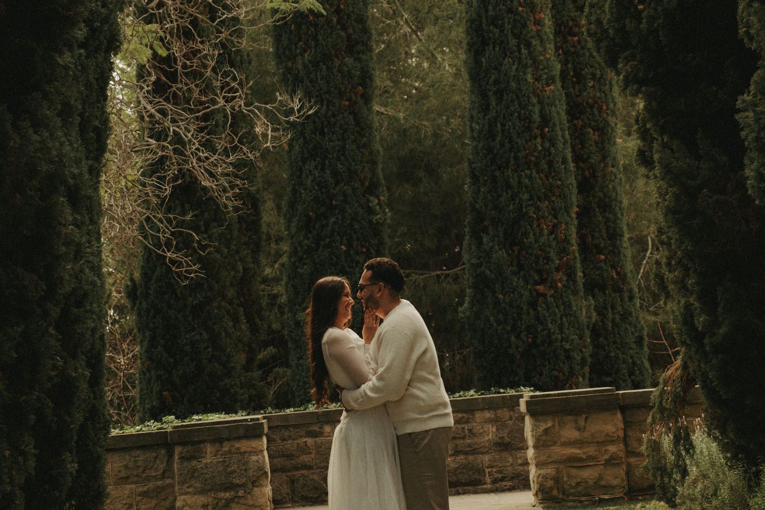 A couple in wedding attire shares a romantic moment in a lush forest setting during their wedding photoshoot.