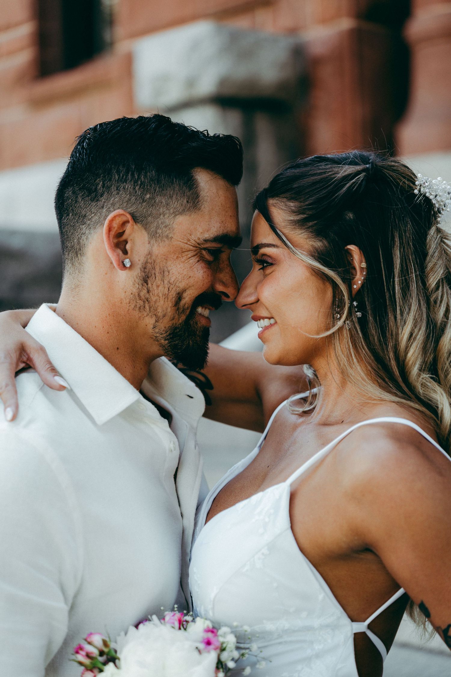 A romantic close-up of newlyweds sharing an intimate moment in white attire.