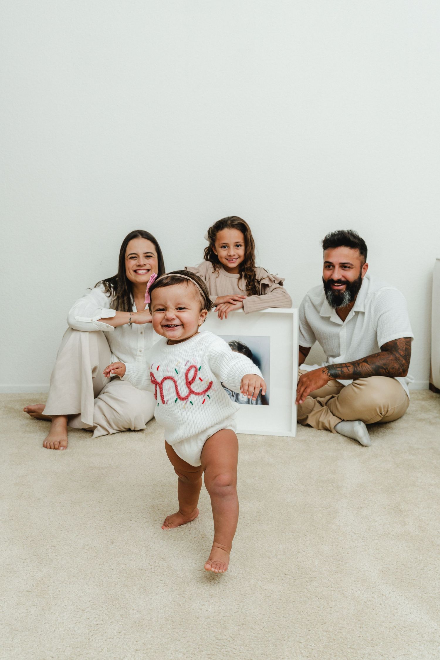 A happy family poses playfully on the floor during a casual photo session.