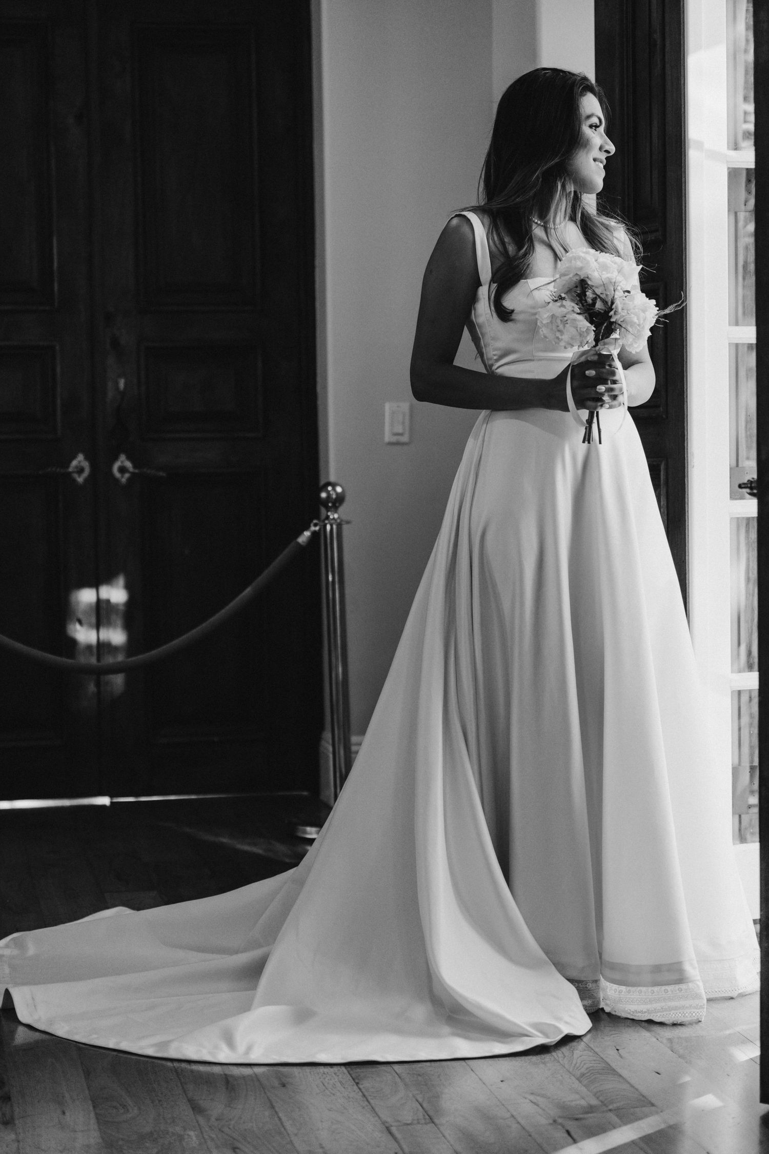 Black and white photos show elegant wedding dress details with flowing train and fabric in an indoor setting.