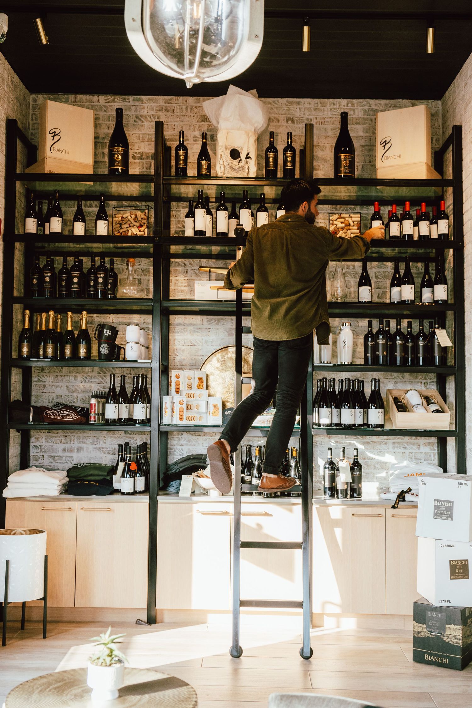 Interior of modern wine shop with shelves of bottles and exposed brick walls.