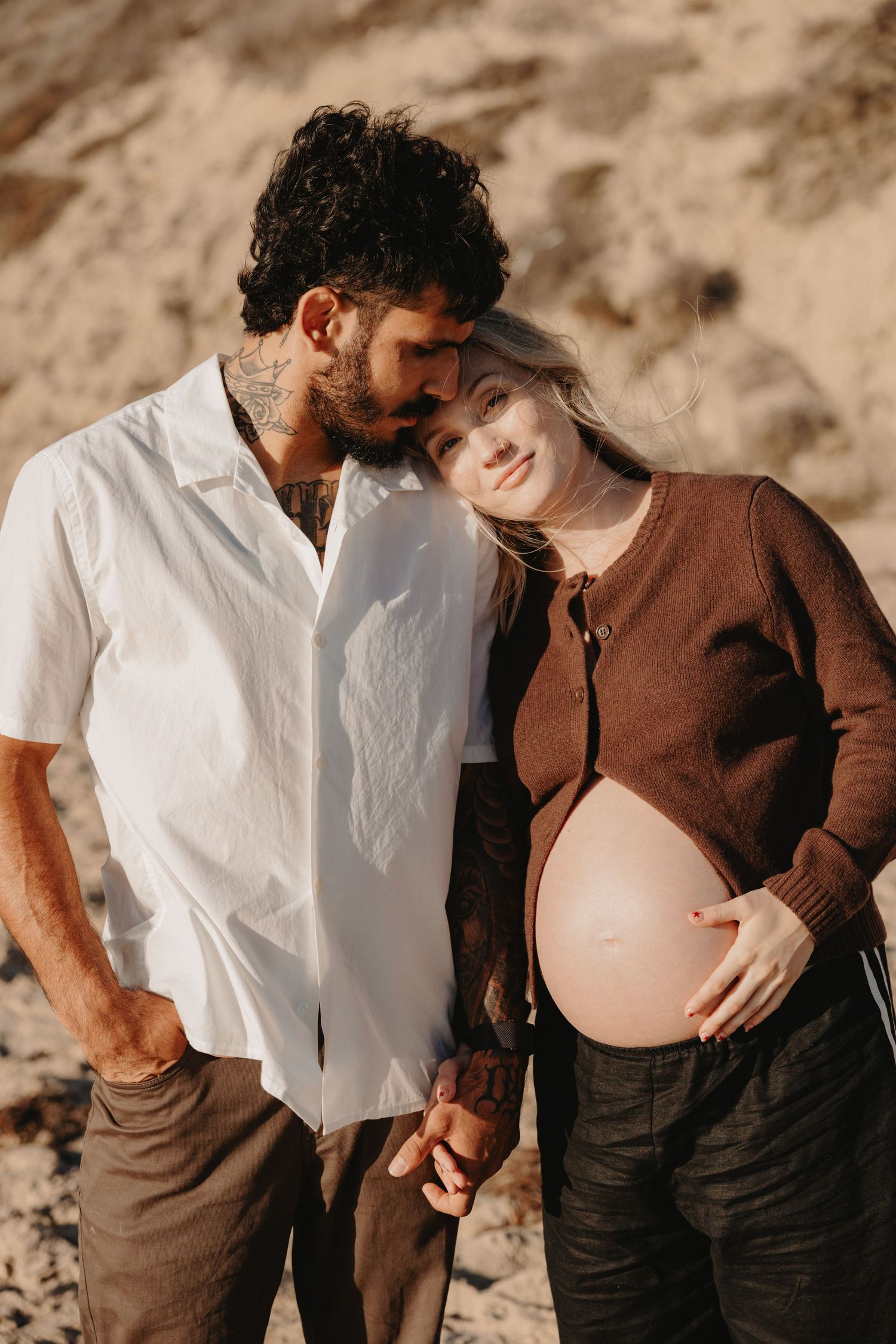 A couple shares an intimate moment outdoors as they celebrate their pregnancy with the woman showing her baby bump.