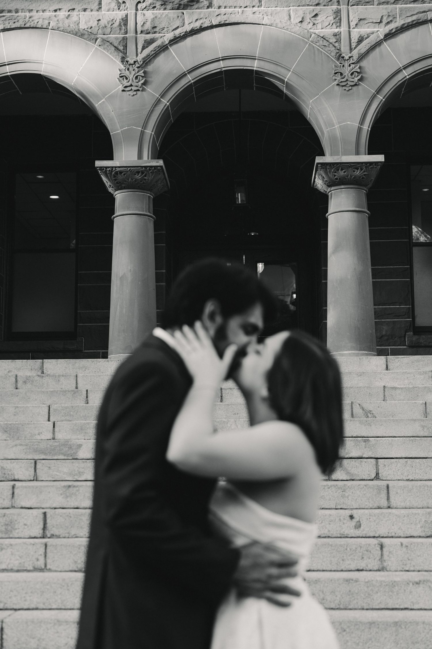 A black and white sequence of romantic dance moves shown against a stone wall with arched columns.