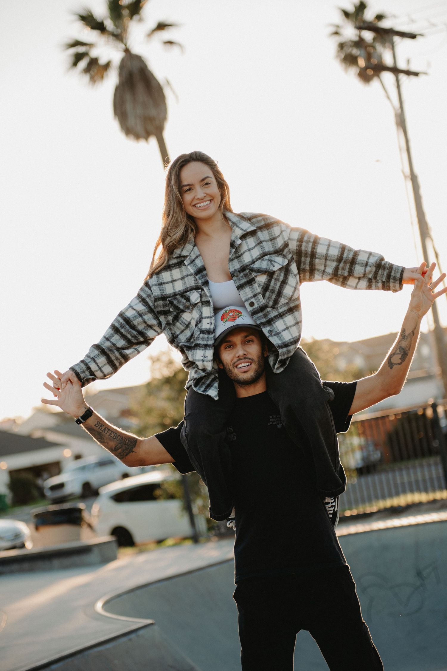 A couple playfully poses together in a series of candid sunset photos with palm trees in the background.
