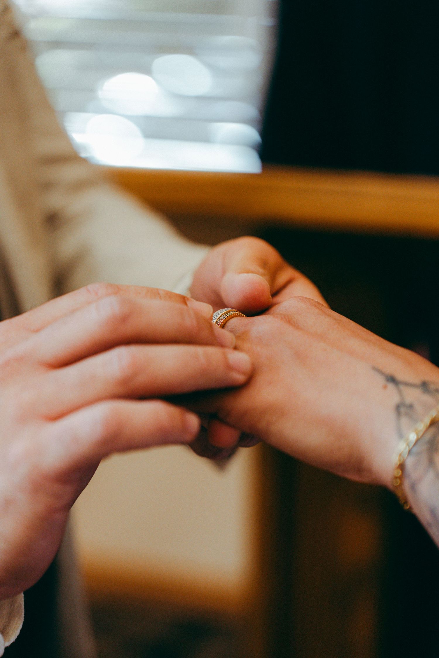 Close-up of two hands tenderly touching with small tattoos visible.
