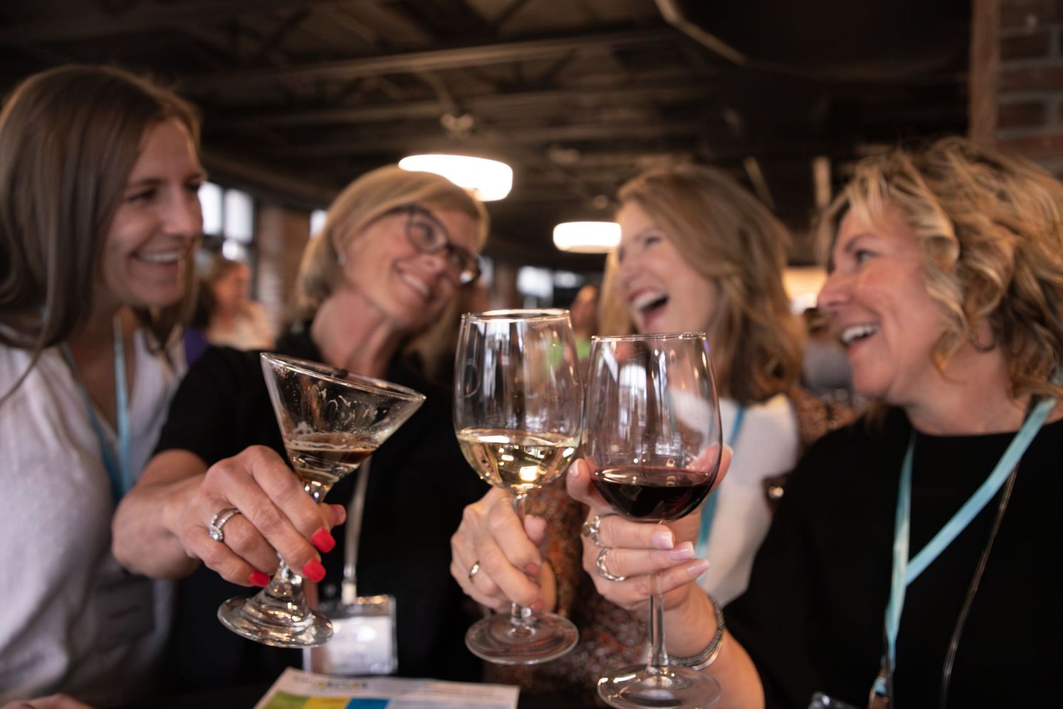 Friends sharing wine and laughter at a casual gathering indoors.