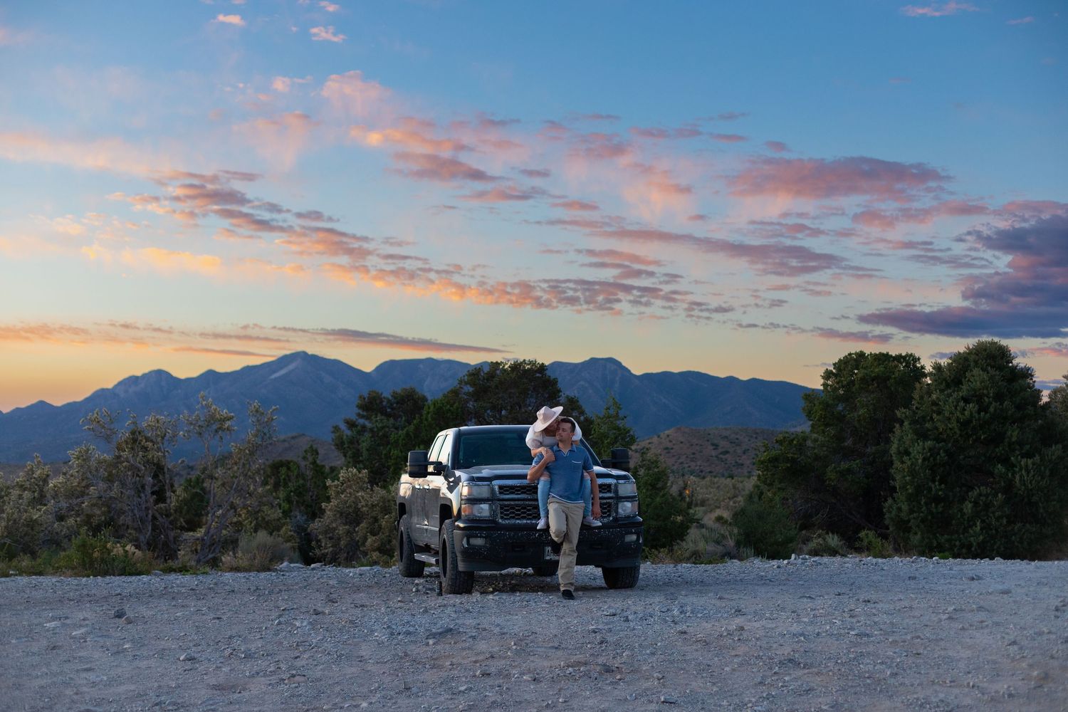 Cars parked in a desert landscape at sunset with mountains in the background.