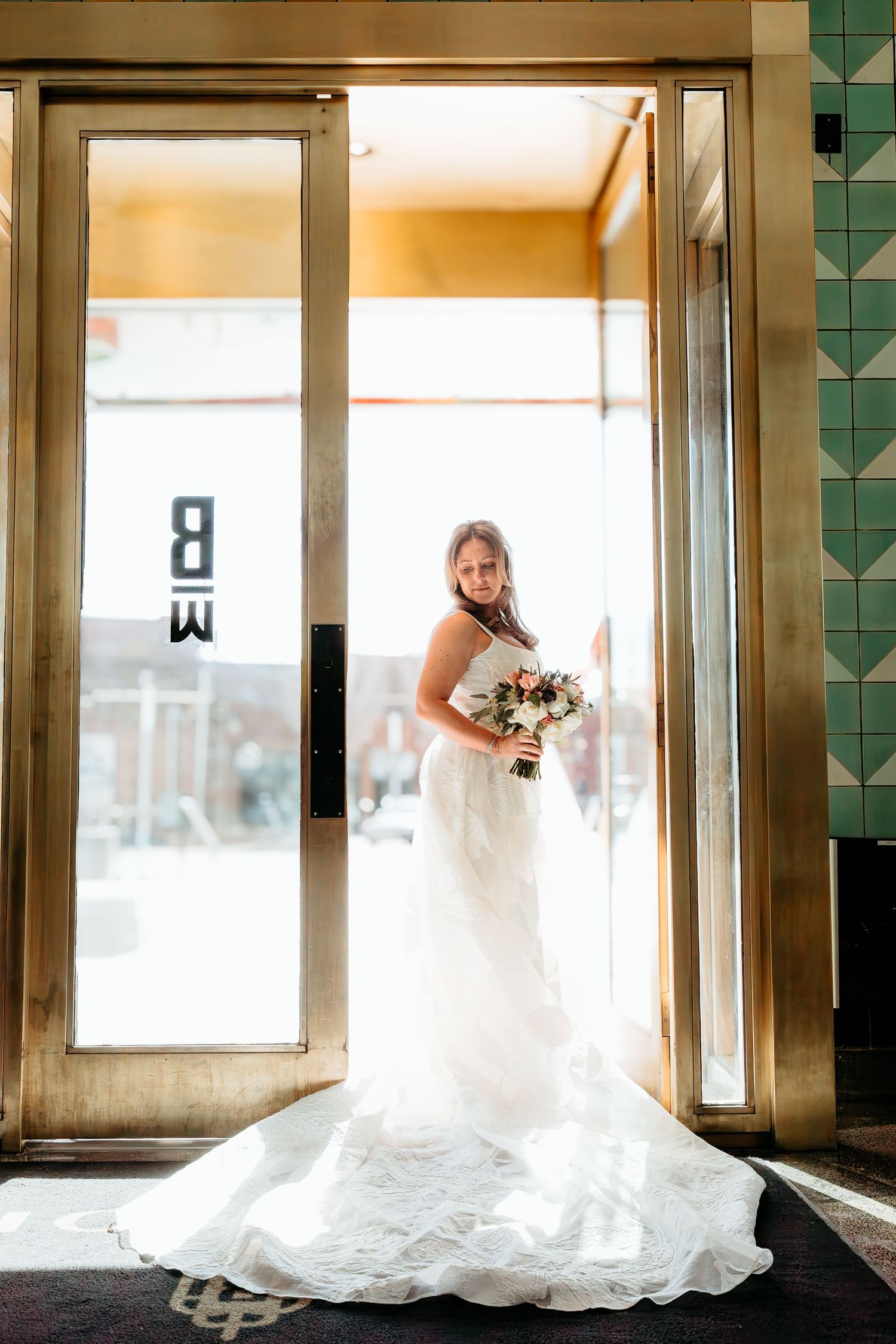 Dramatic bridal portrait series showcasing flowing white wedding dress train in art deco doorway.