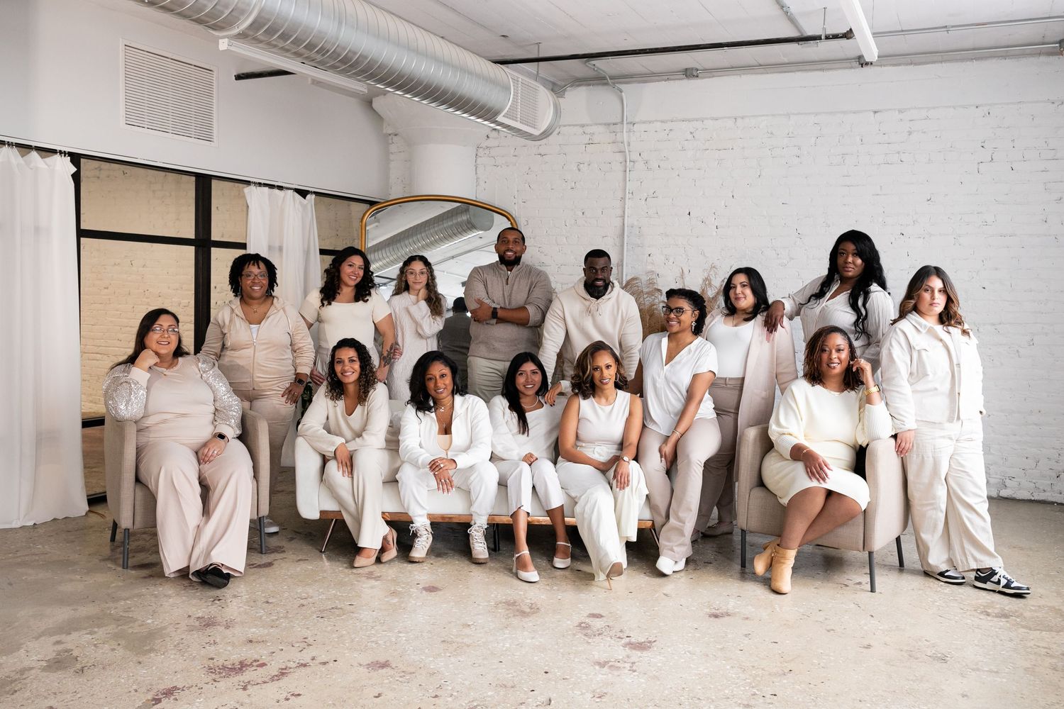 Group photo session with people wearing all white clothing in a studio setting.