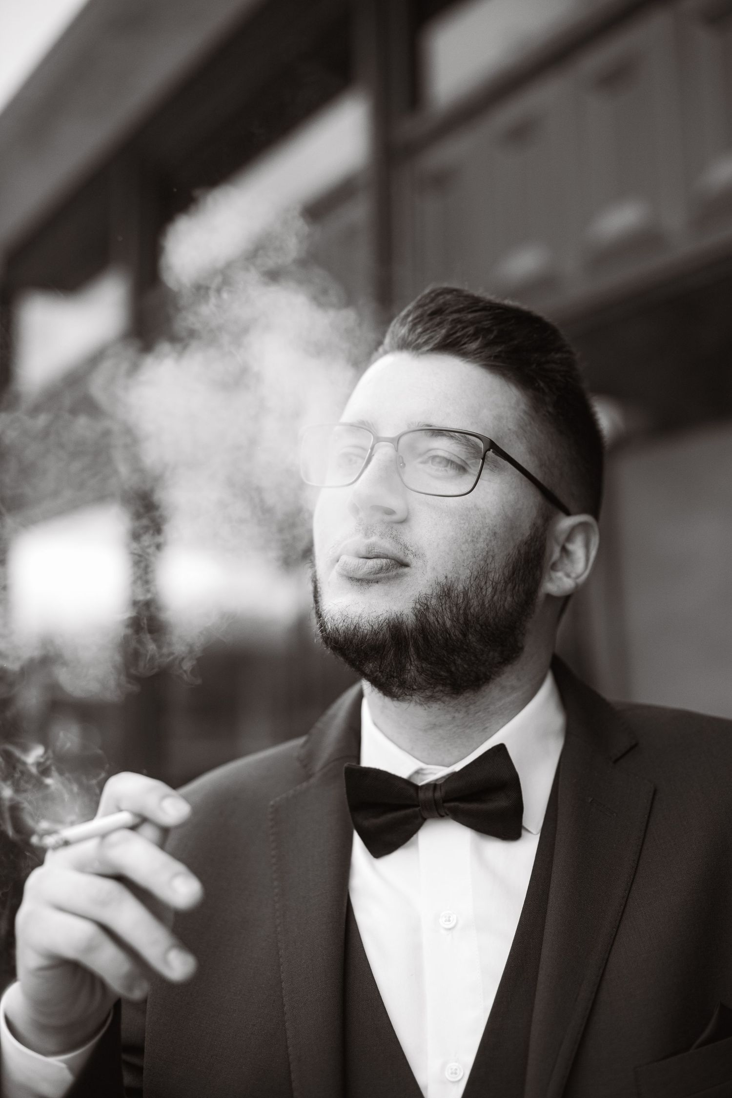 Black and white portraits of person in formal attire smoking.