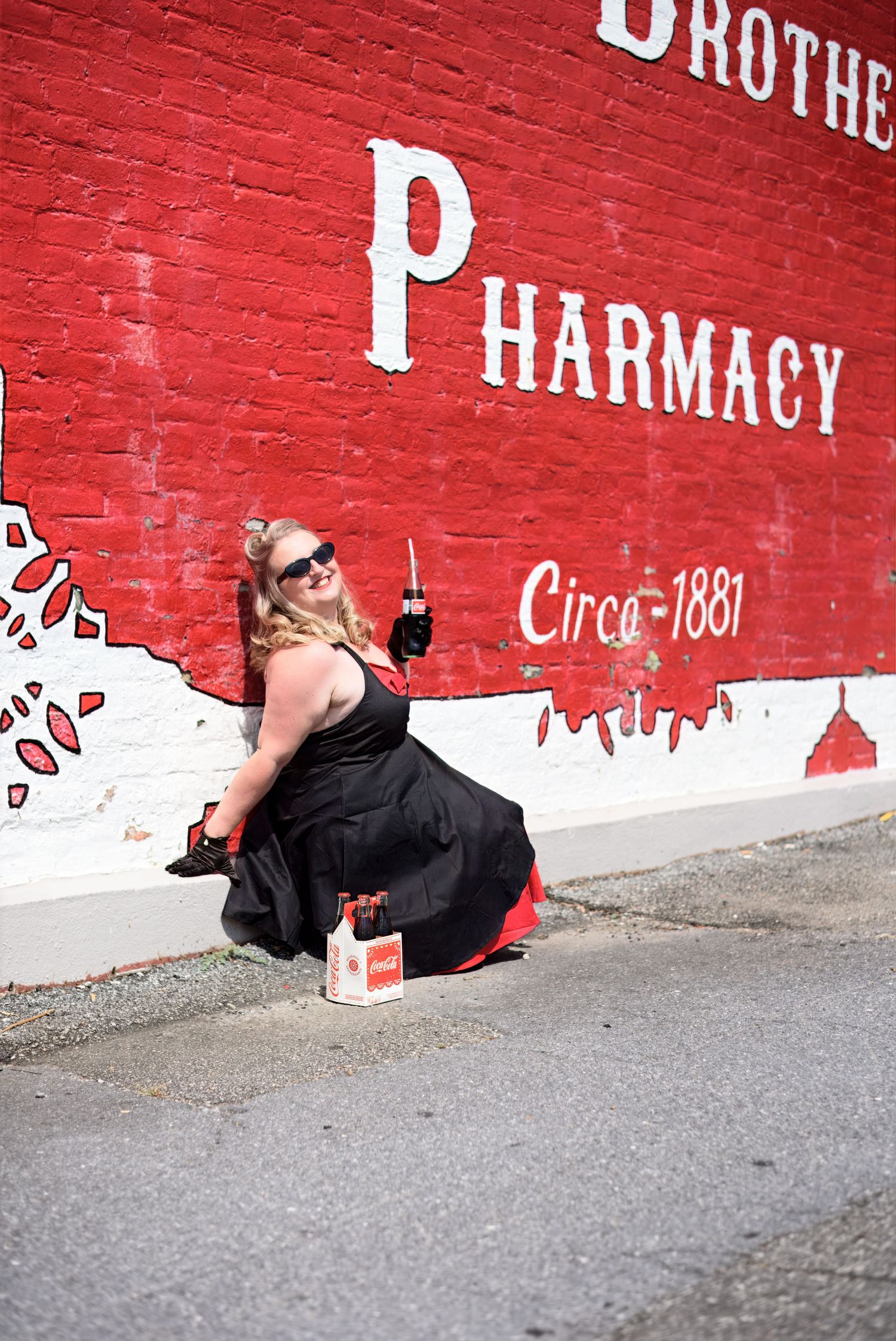 A creative photo series against a red brick wall with white pharmacy lettering.  First and oldest Coca Cola advertisement wall in history.