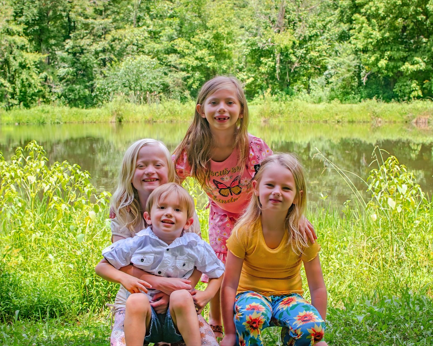 A group enjoys a sunny summer day in a lush meadow filled with wildflowers and tall grass.