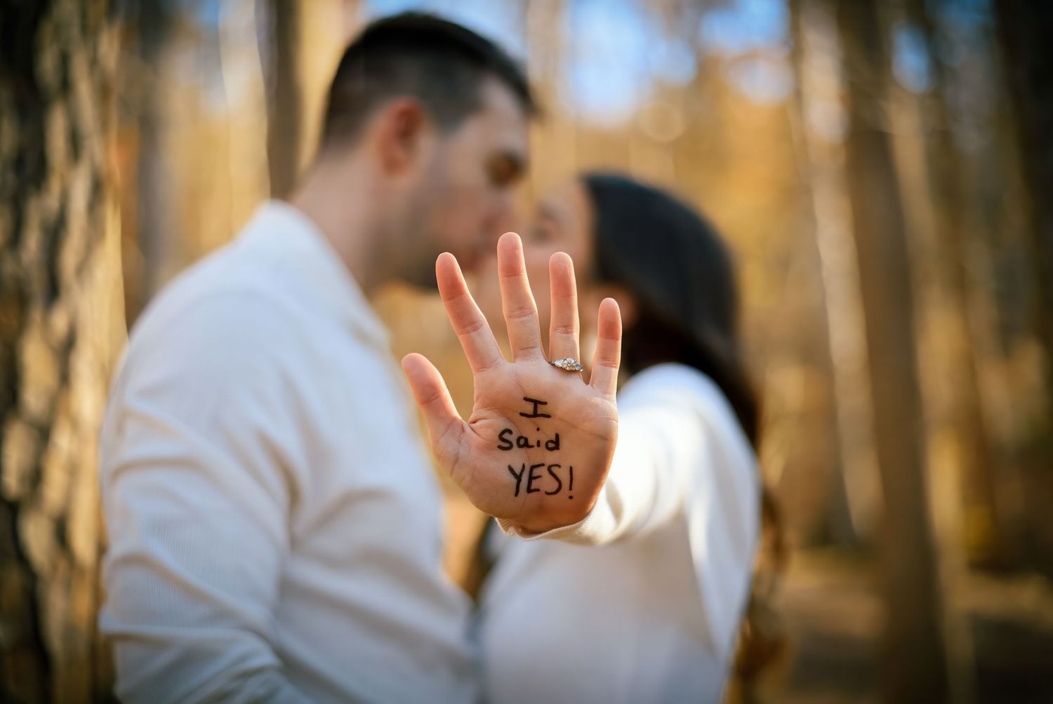Engagement close-up of hand with writing against blurred forest background.