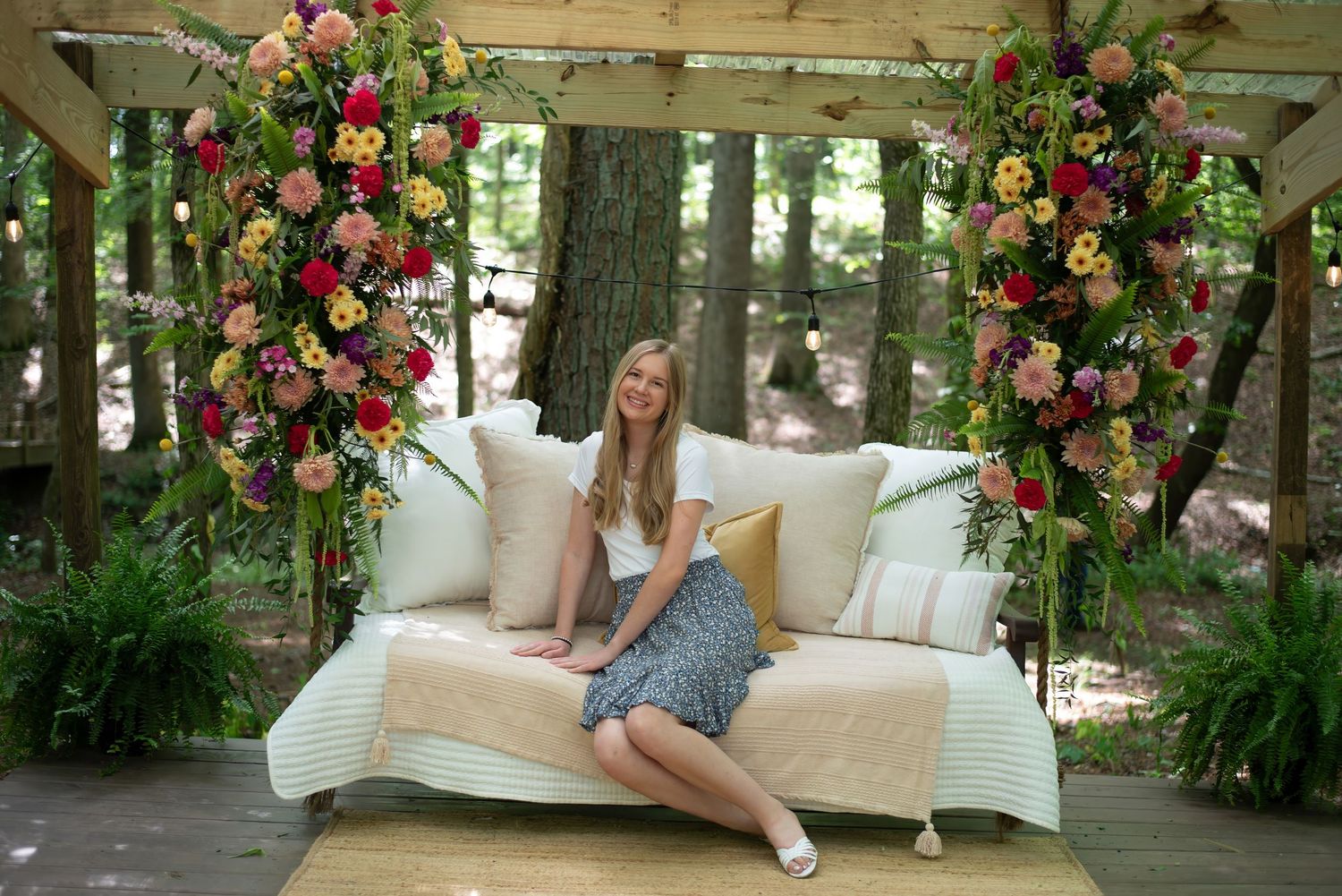Elegant outdoor wedding swing adorned with lush pink and red floral arrangements in a garden setting.
