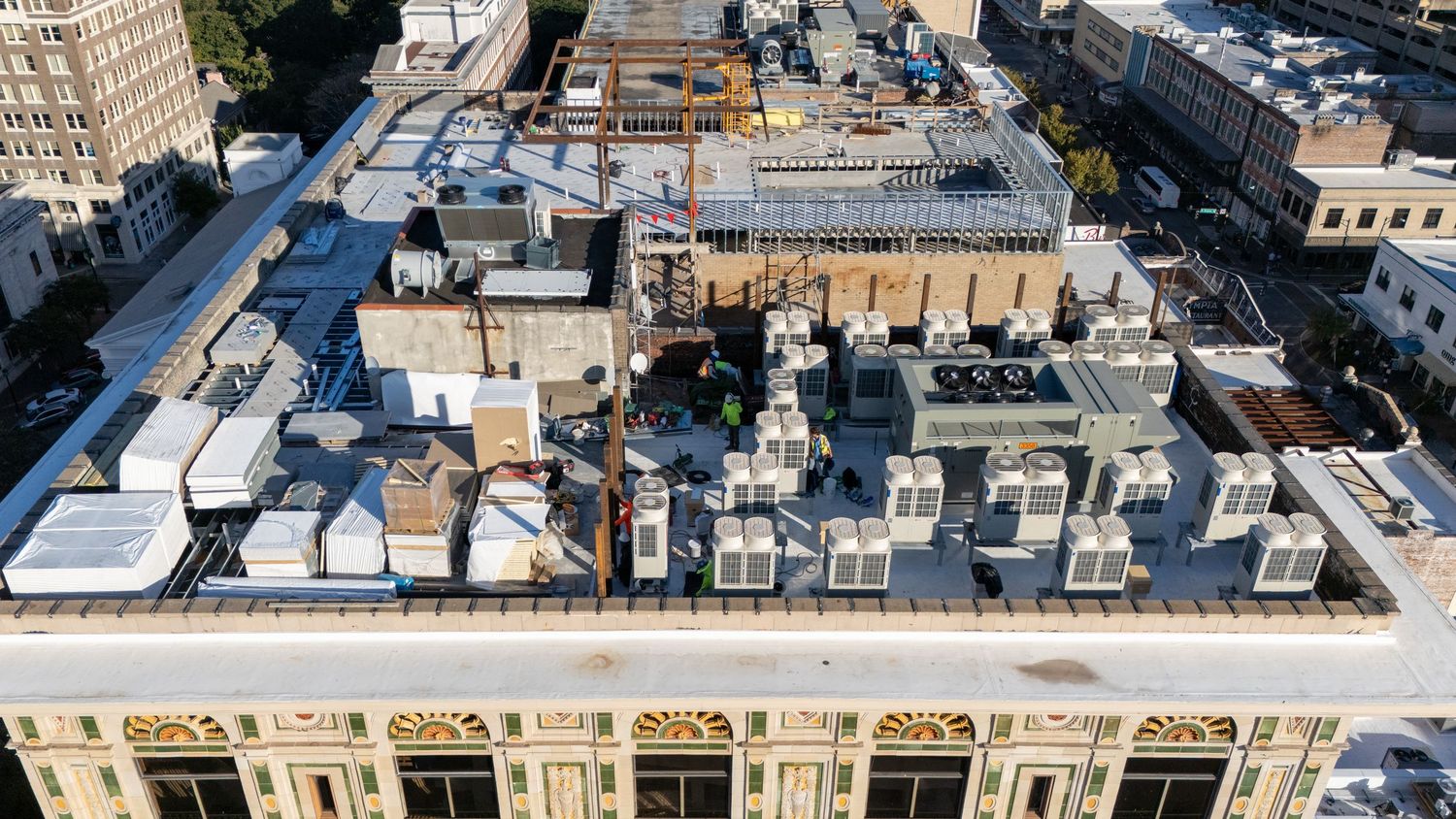 Aerial panoramic view of historic buildings and rooftops in a dense urban neighborhood.  People working on a new project on the rooftop.