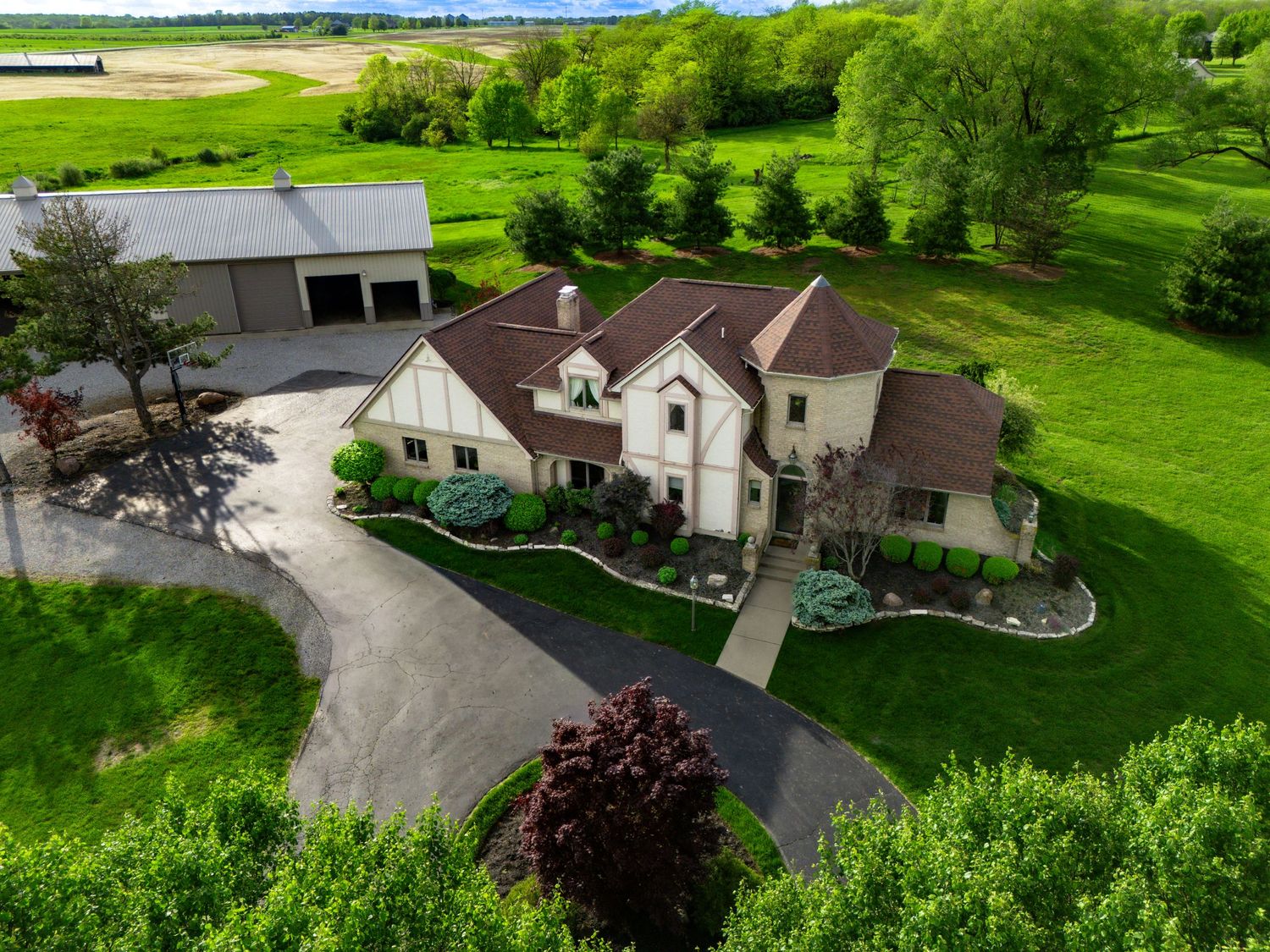 Aerial view of a spacious country property with multiple buildings and driveways surrounded by lush green landscape.