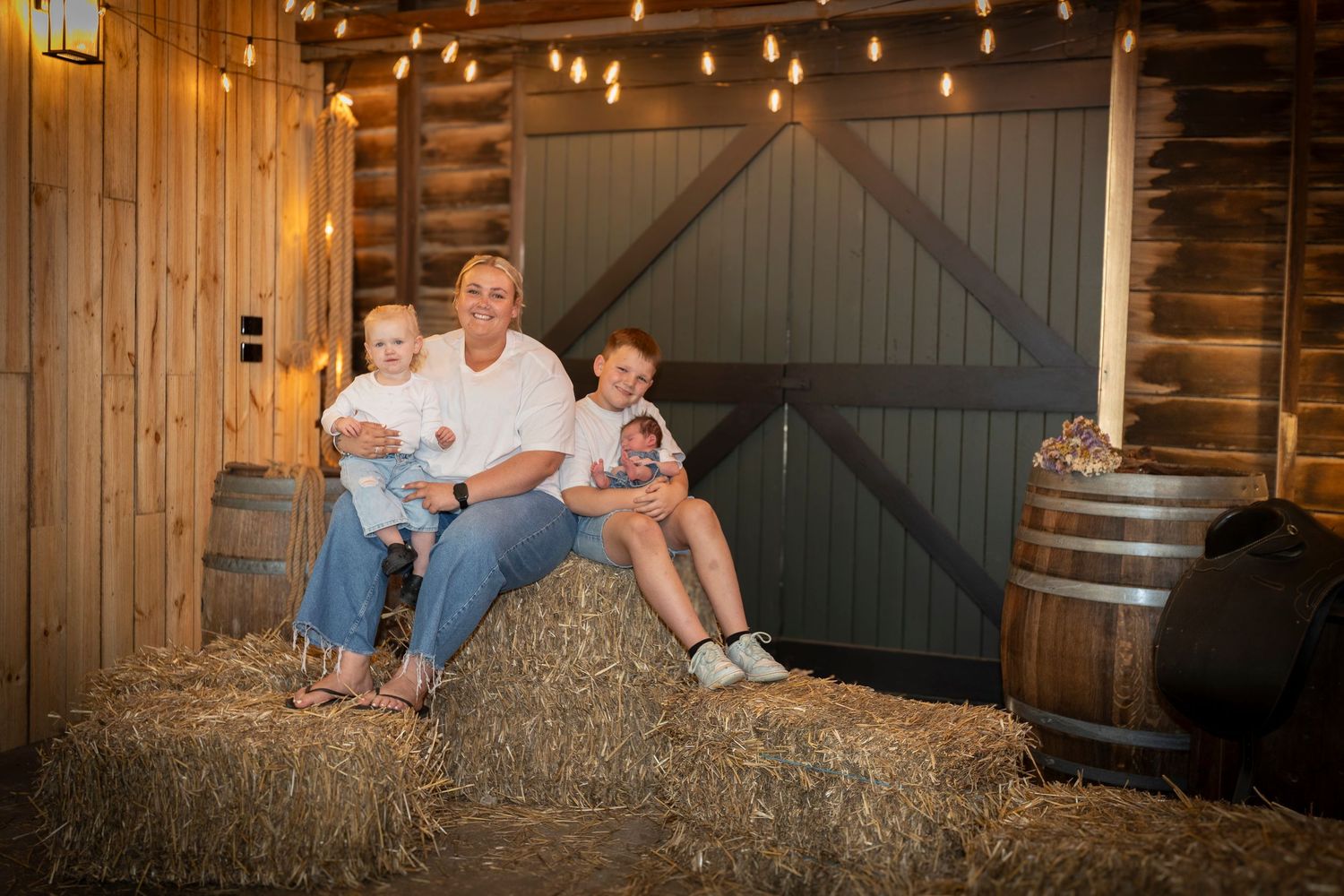 A rustic barn interior with string lights and hay bales creates a cozy autumn atmosphere.