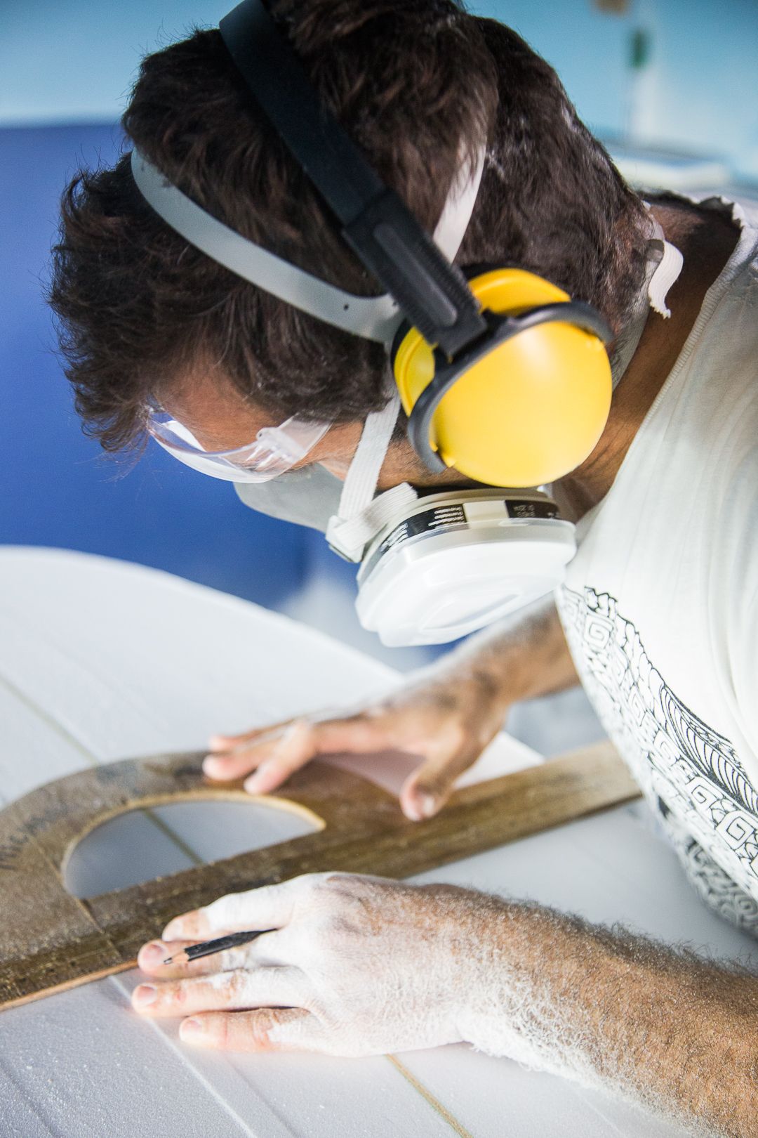 Craftsperson wearing protective gear works on sanding and finishing a wooden surface with precision and care.