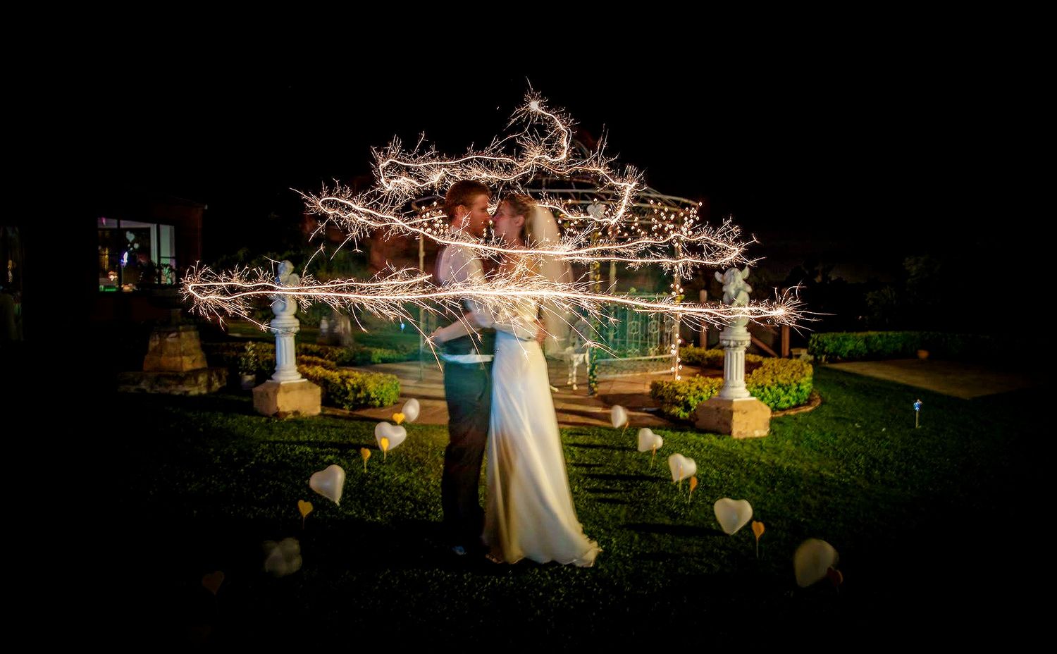 A magical outdoor wedding scene with illuminated branches and decorative elements glowing against the night sky.