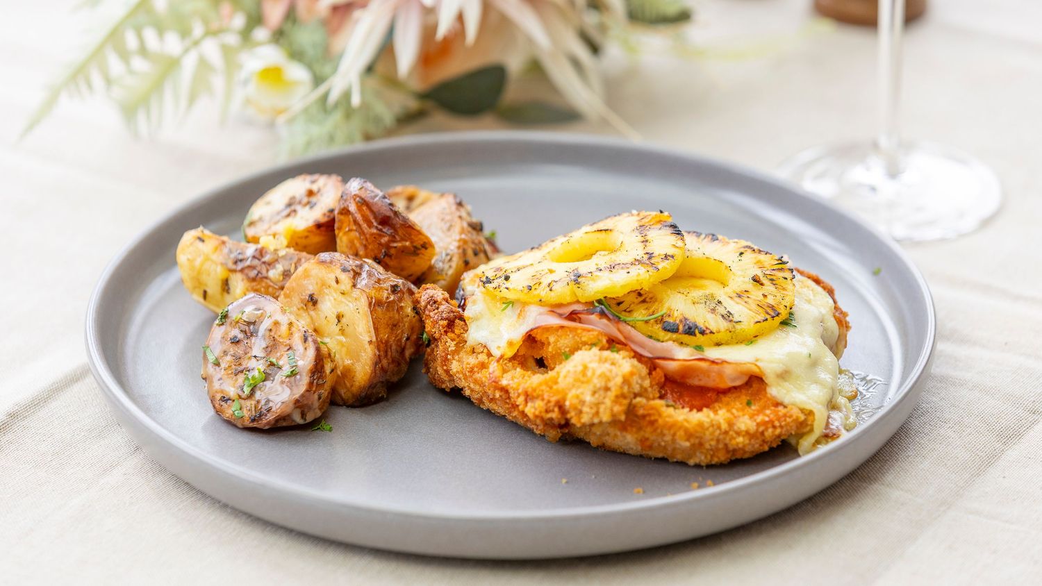 Roasted lemon herb chicken breast with crispy skin and herbs served on a gray ceramic plate.