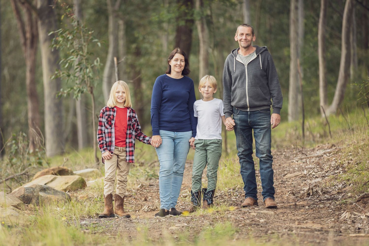 Photo Link to information on Family  Photography Sessions. Family stands together on a wooded trail with their small dog.