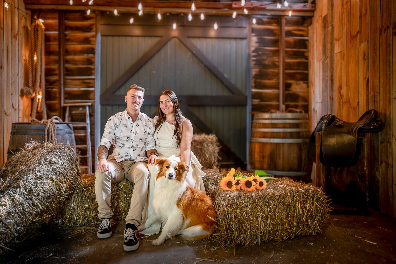 Rustic barn wedding venue decorated with string lights and hay bales creates a cozy, romantic atmosphere.
