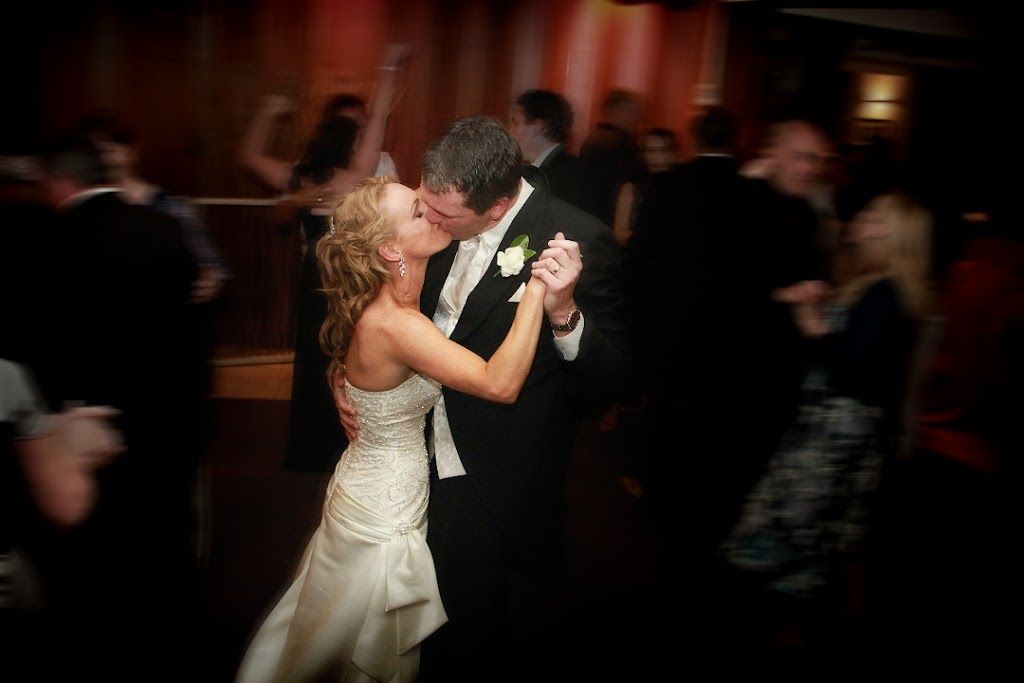 A bride and groom share their first dance together at a dimly lit wedding reception.